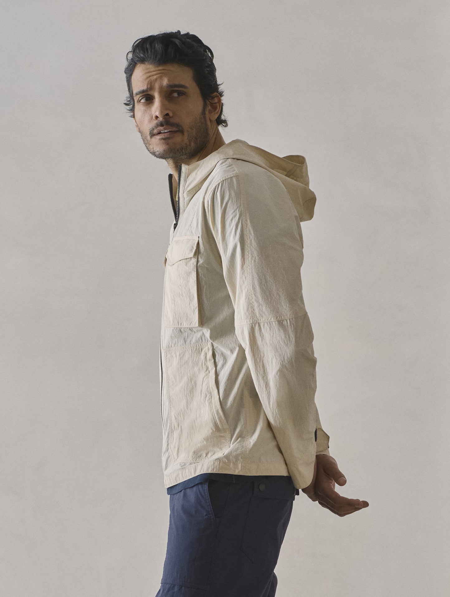 Side profile view of man wearing Aires Lightweight Windbreaker in Bone white from AETHER Apparel.