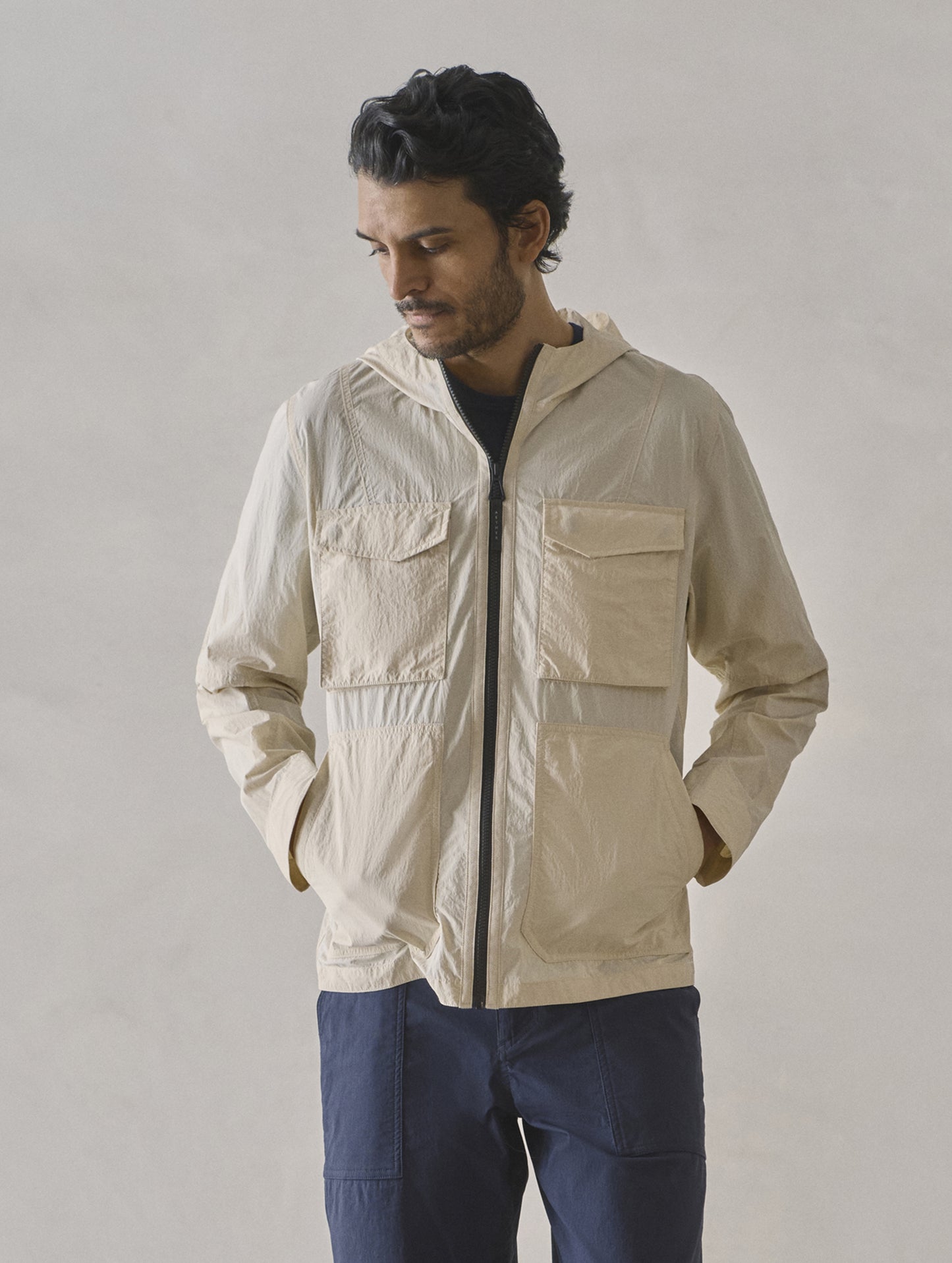 Front upper body view of man wearing Aires Lightweight Windbreaker in Bone white from AETHER Apparel.