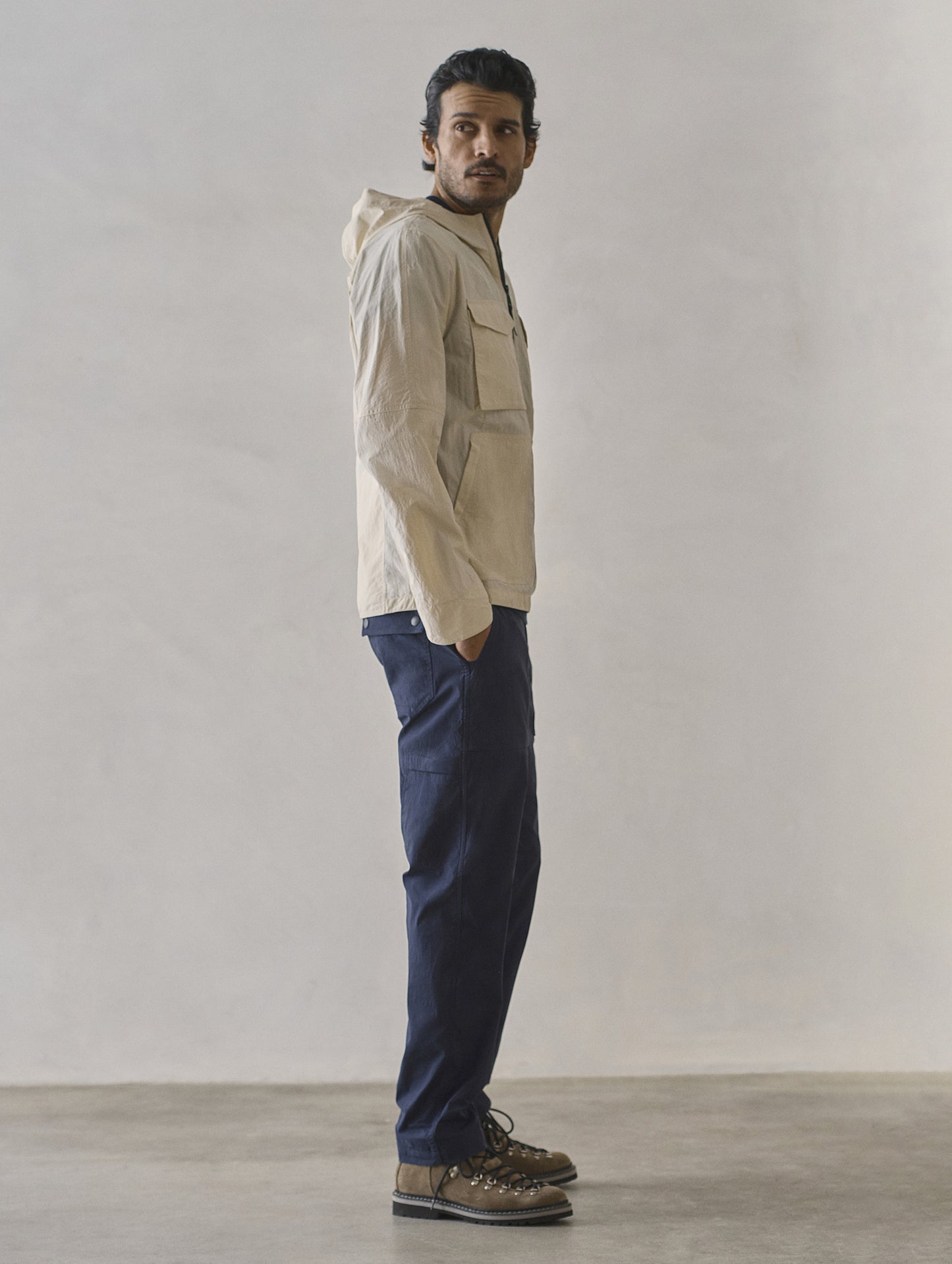 Full-body side profile view of man wearing Aires Lightweight Windbreaker in Bone white from AETHER Apparel.