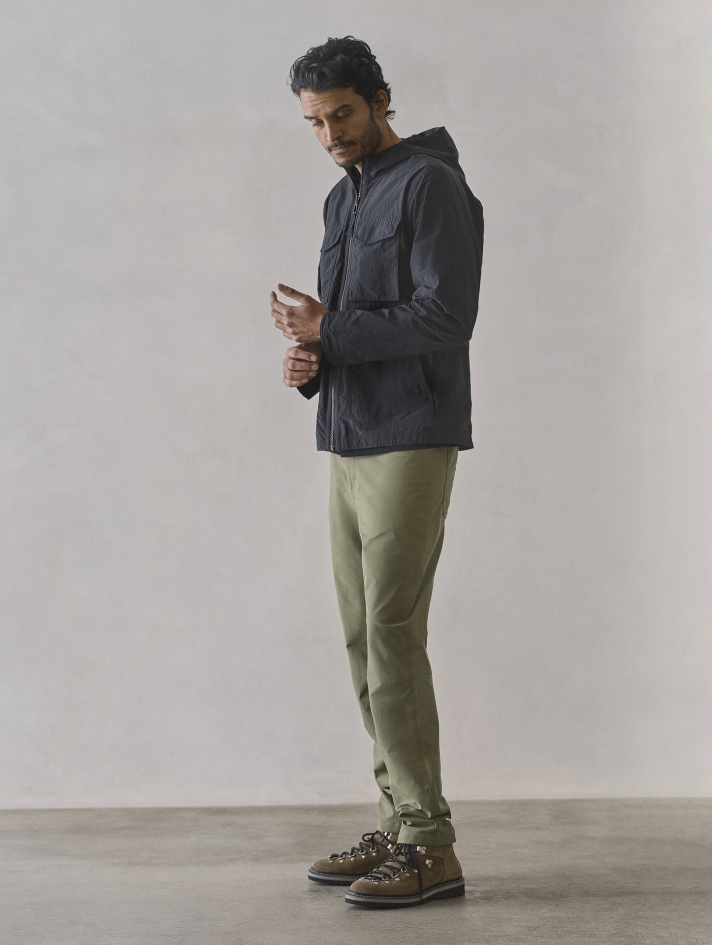 Full-body side profile view of man wearing Aires Lightweight Windbreaker in Onyx Black from AETHER Apparel.