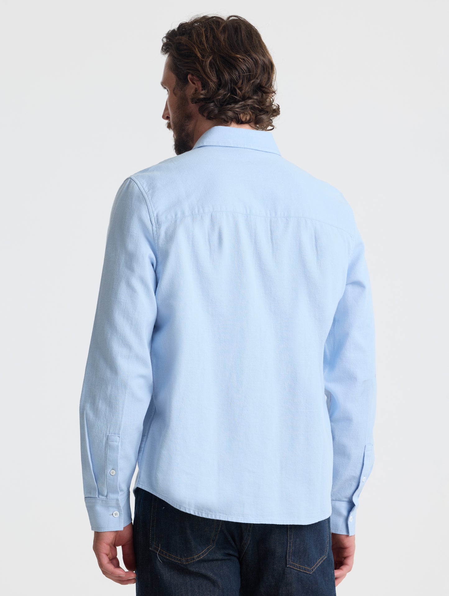 Rear view of man wearing Alder Chambray Button-Down in Light Blue from AETHER Apparel.