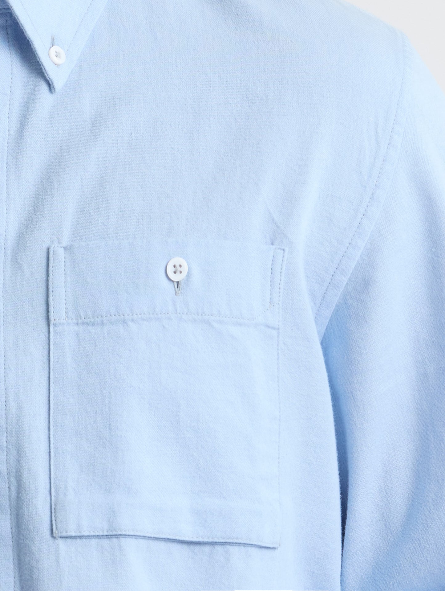 Closeup view of chest pocket of Alder Chambray Button-Down in Light Blue from AETHER Apparel.