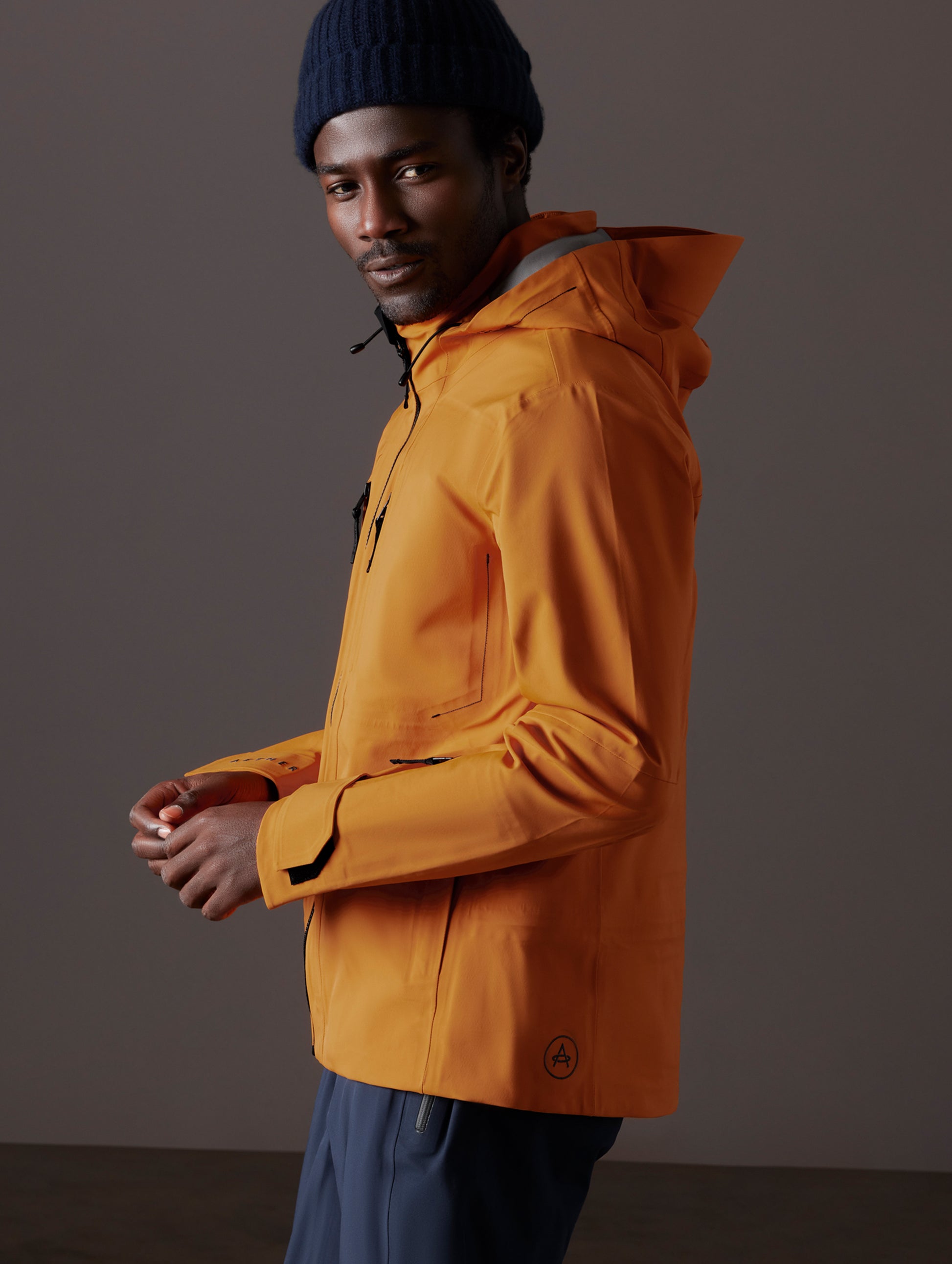 Side profile body view of man wearing Altitude Snow Shell 2.0 in Autumn Orange from AETHER Apparel.