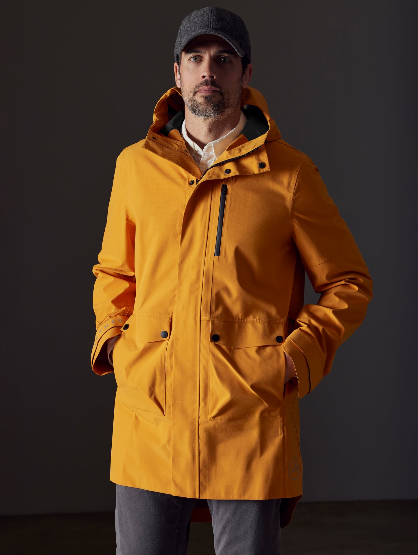 Front body view of man wearing Anders Rain Jacket in Midas Orange from AETHER Apparel.