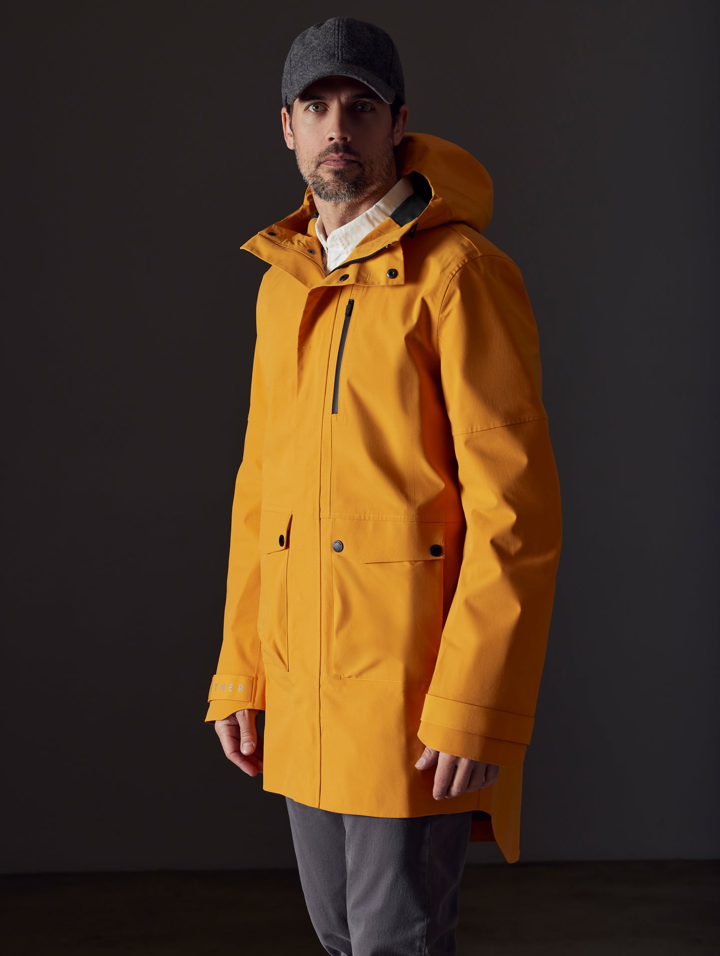 Front 3/4 body view of man wearing Anders Rain Jacket in Midas Orange from AETHER Apparel.