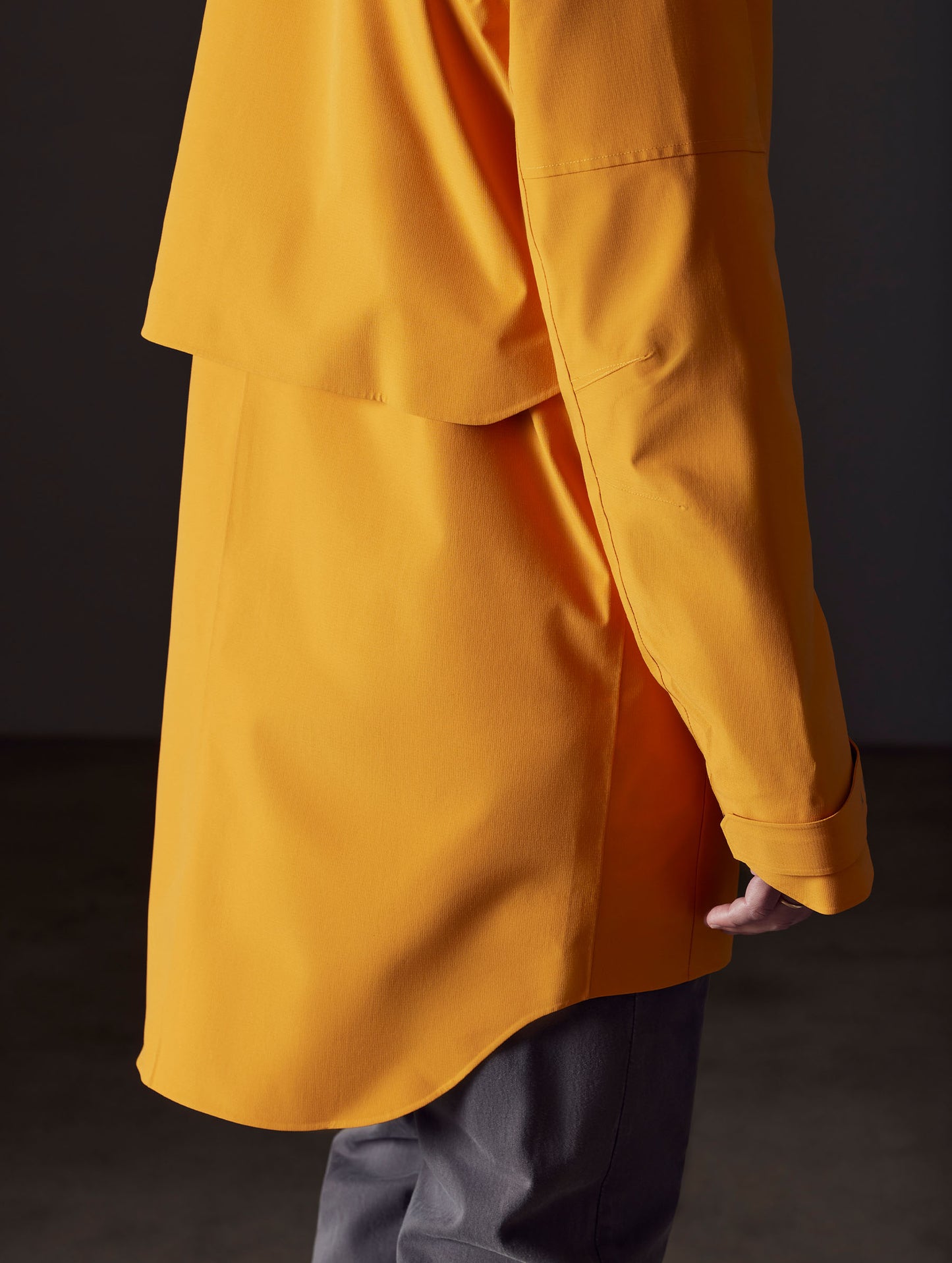 Detailed view of the vented storm shield on the Anders Rain Jacket in Midas Orange from AETHER Apparel.
