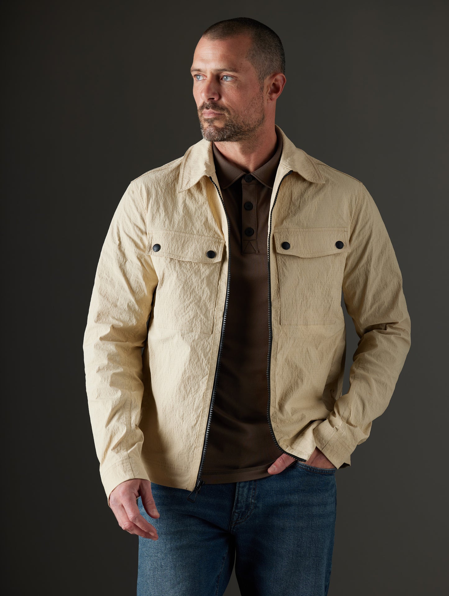 Front body view of man wearing unzipped Baxter Jacket in Desert Tan from AETHER Apparel.