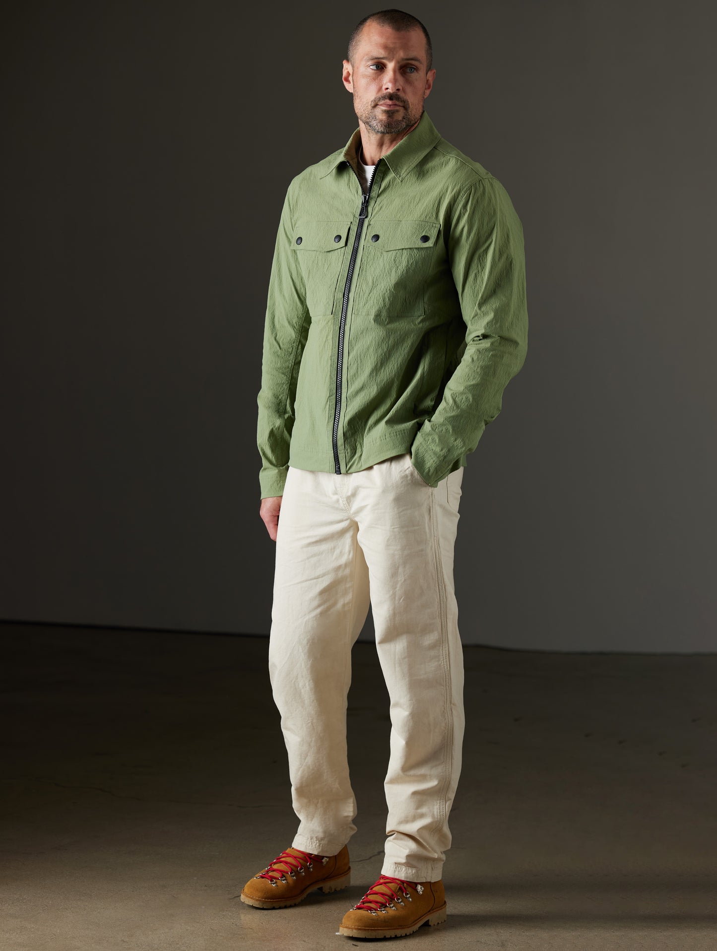 Front 3/4 full-body view of man wearing Baxter Jacket in Mineral Green from AETHER Apparel.