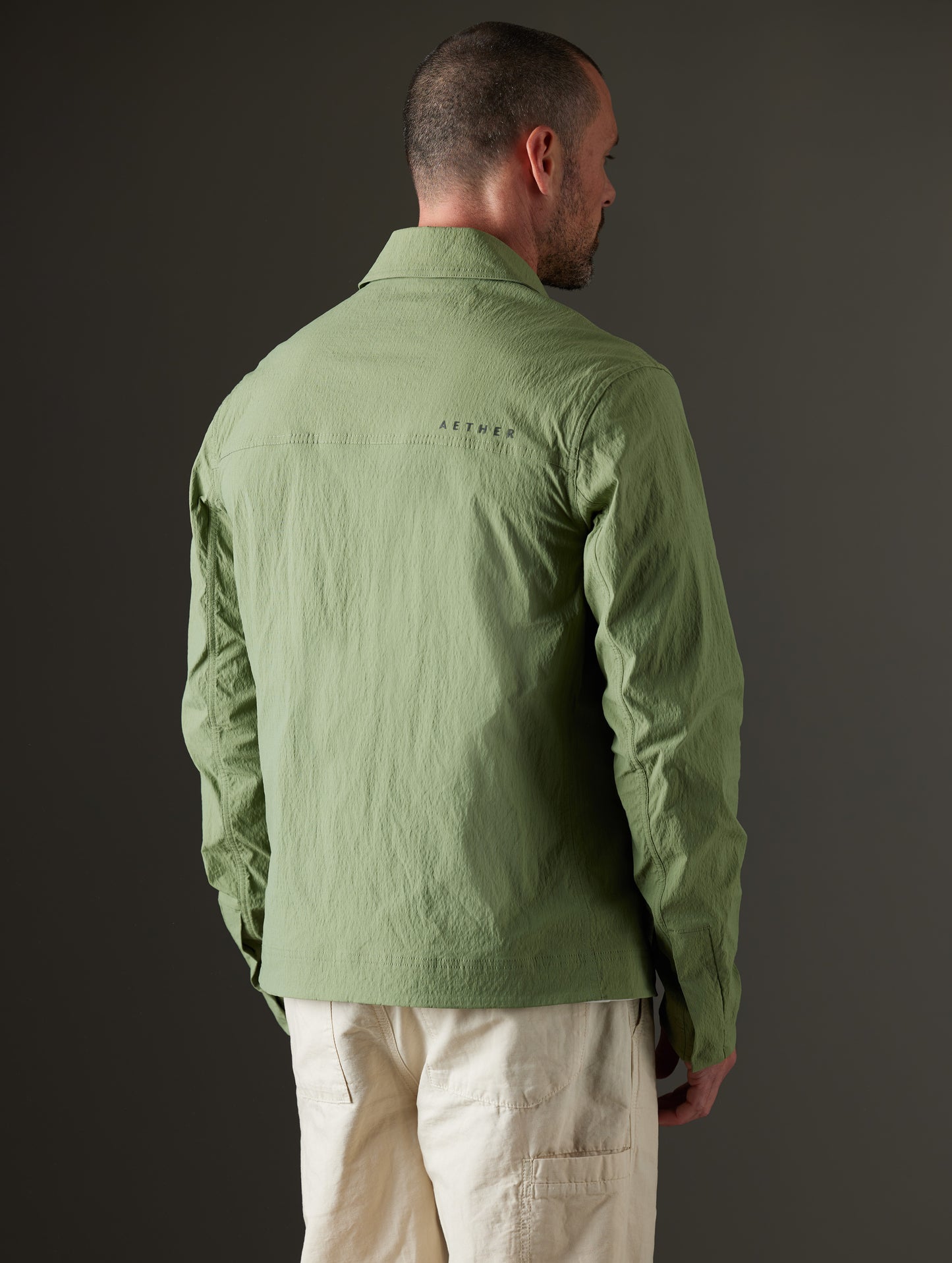 Rear 3/4 body view of man wearing Baxter Jacket in Mineral Green from AETHER Apparel.
