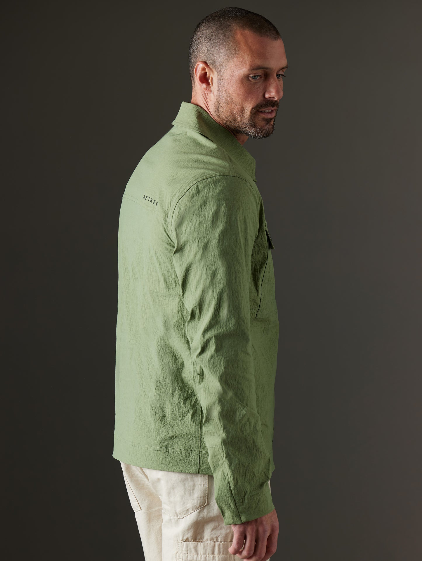 Side profile body view of man wearing Baxter Jacket in Mineral Green from AETHER Apparel.
