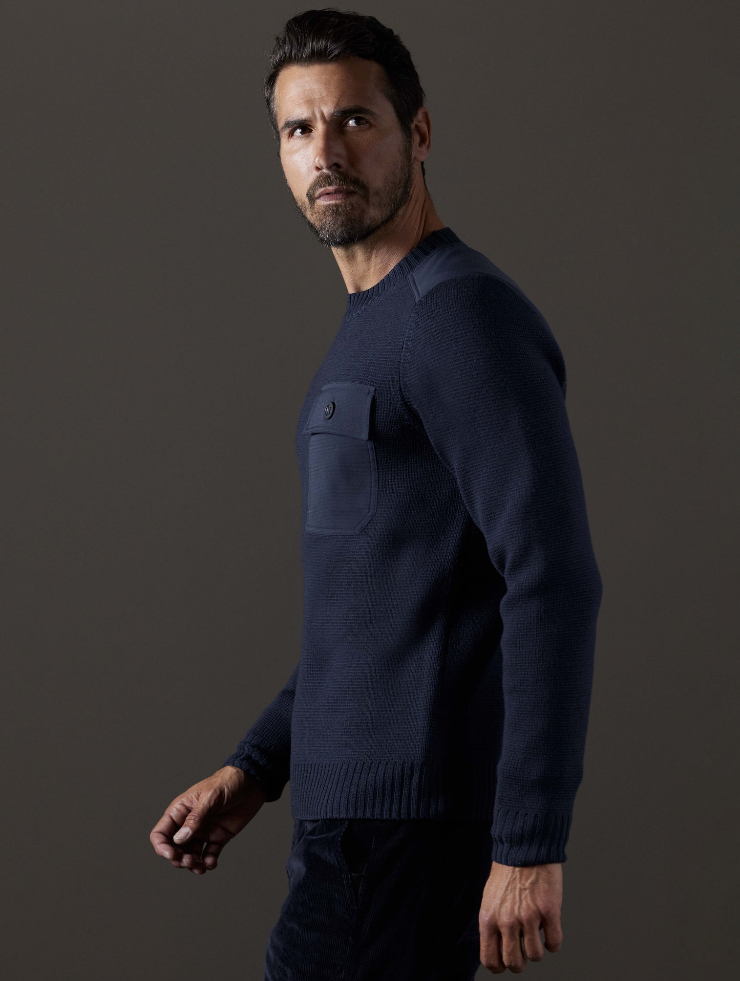 Side profile body view of man wearing Benson Crewneck Sweater in Total Eclipse dark blue from AETHER Apparel.