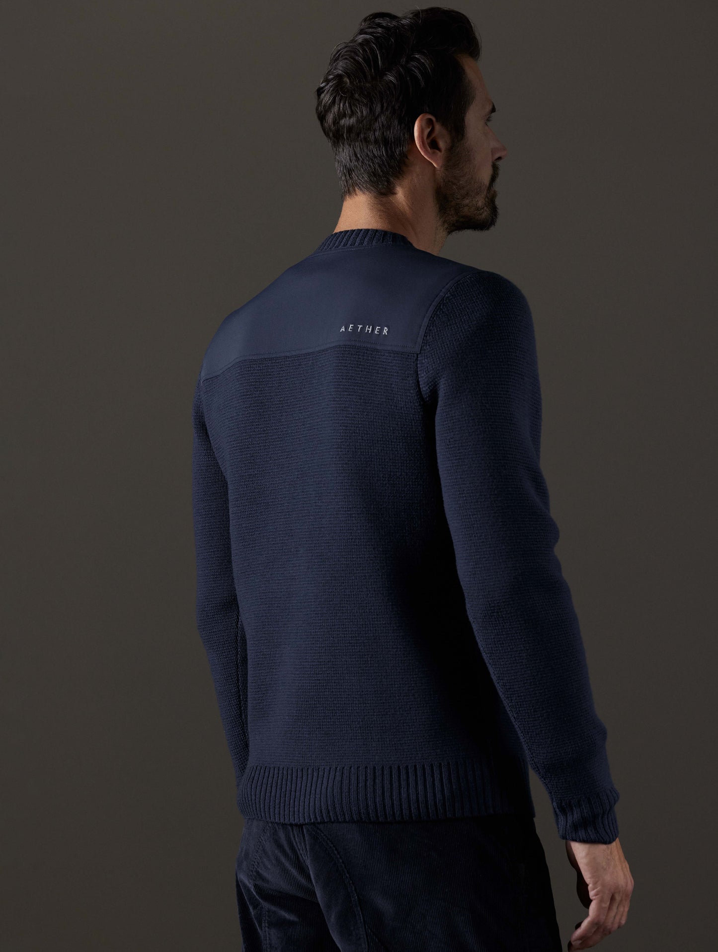 Rear 3/4 body view of man wearing Benson Crewneck Sweater in Total Eclipse dark blue from AETHER Apparel.