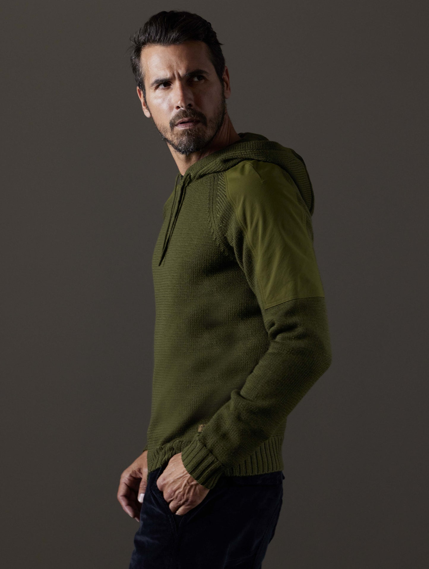 Side profile body view of man wearing Benson Hooded Sweater in Command Green from AETHER Apparel.