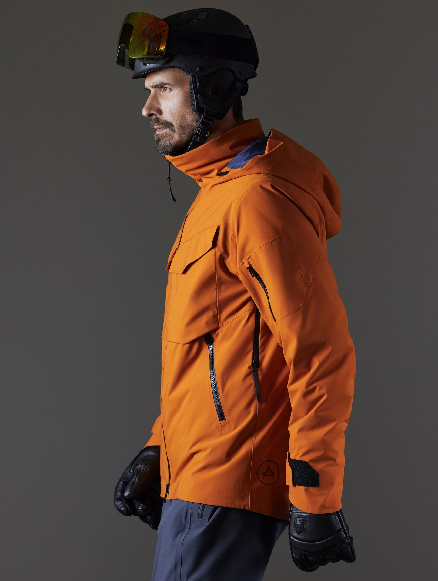 Side profile body view of man wearing Brighton Insulated Snow Jacket in Autumn Orange from AETHER Apparel.