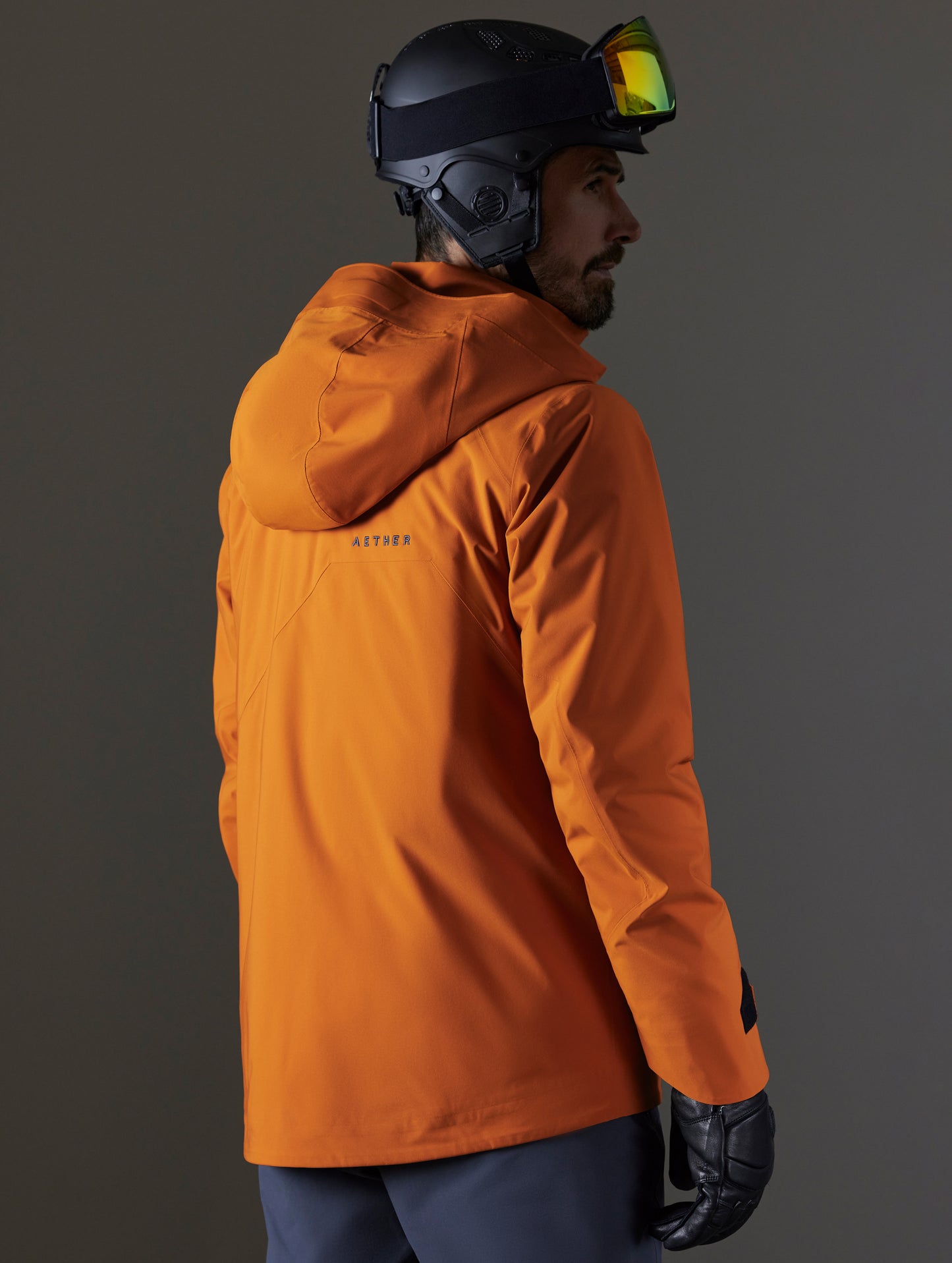 Rear 3/4 body view of man wearing Brighton Insulated Snow Jacket in Autumn Orange from AETHER Apparel.