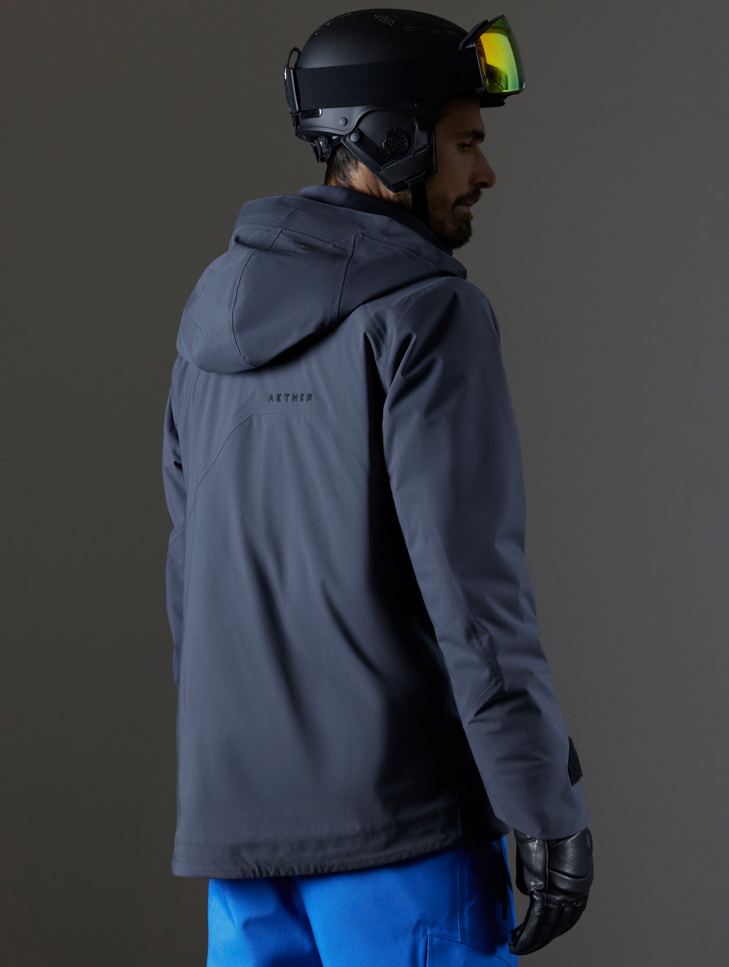 Rear 3/4 body view of man wearing Brighton Insulated Snow Jacket in Graphite from AETHER Apparel.