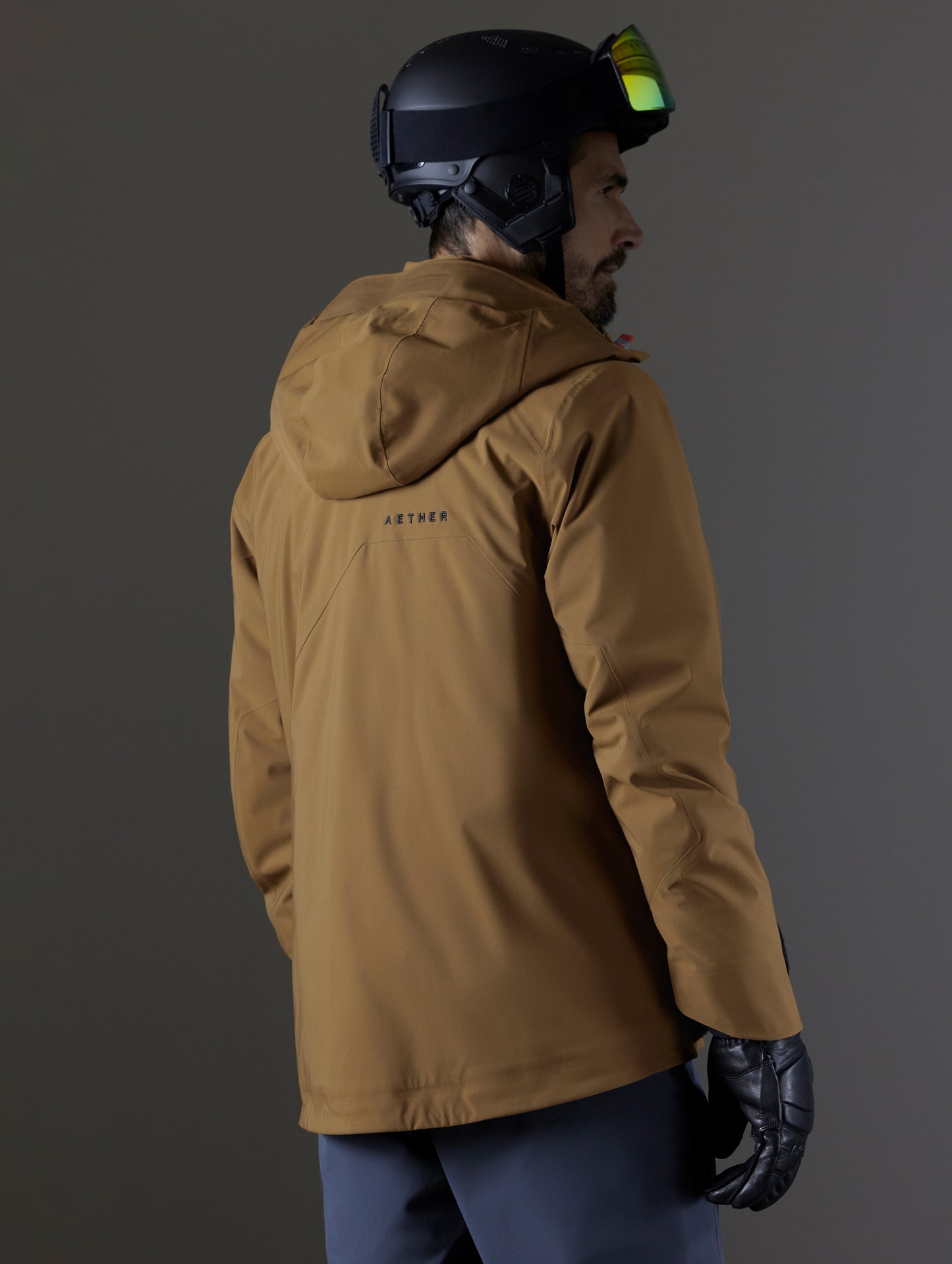 Rear 3/4 body view of man wearing Brighton Insulated Snow Jacket in Rubber Brown from AETHER Apparel.