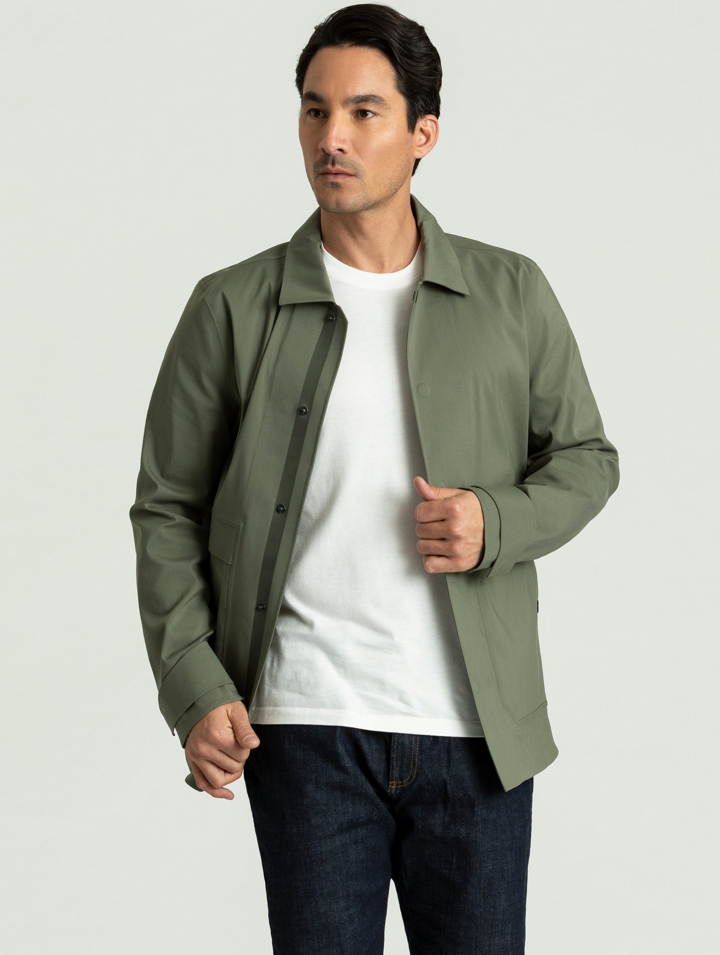 Man wearing open Cole Jacket in spruce green atop white tee from AETHER Apparel.