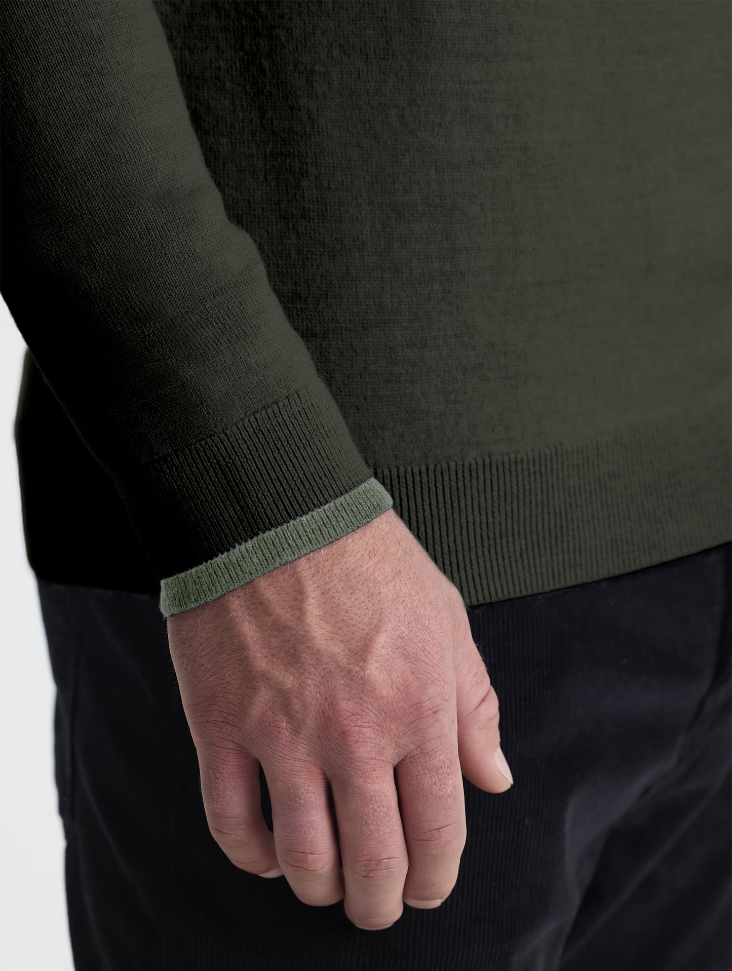 Closeup detail view of wearer's right sleeve of Corbin Sweater in Forest Green with contrast light green hem from AETHER Apparel.