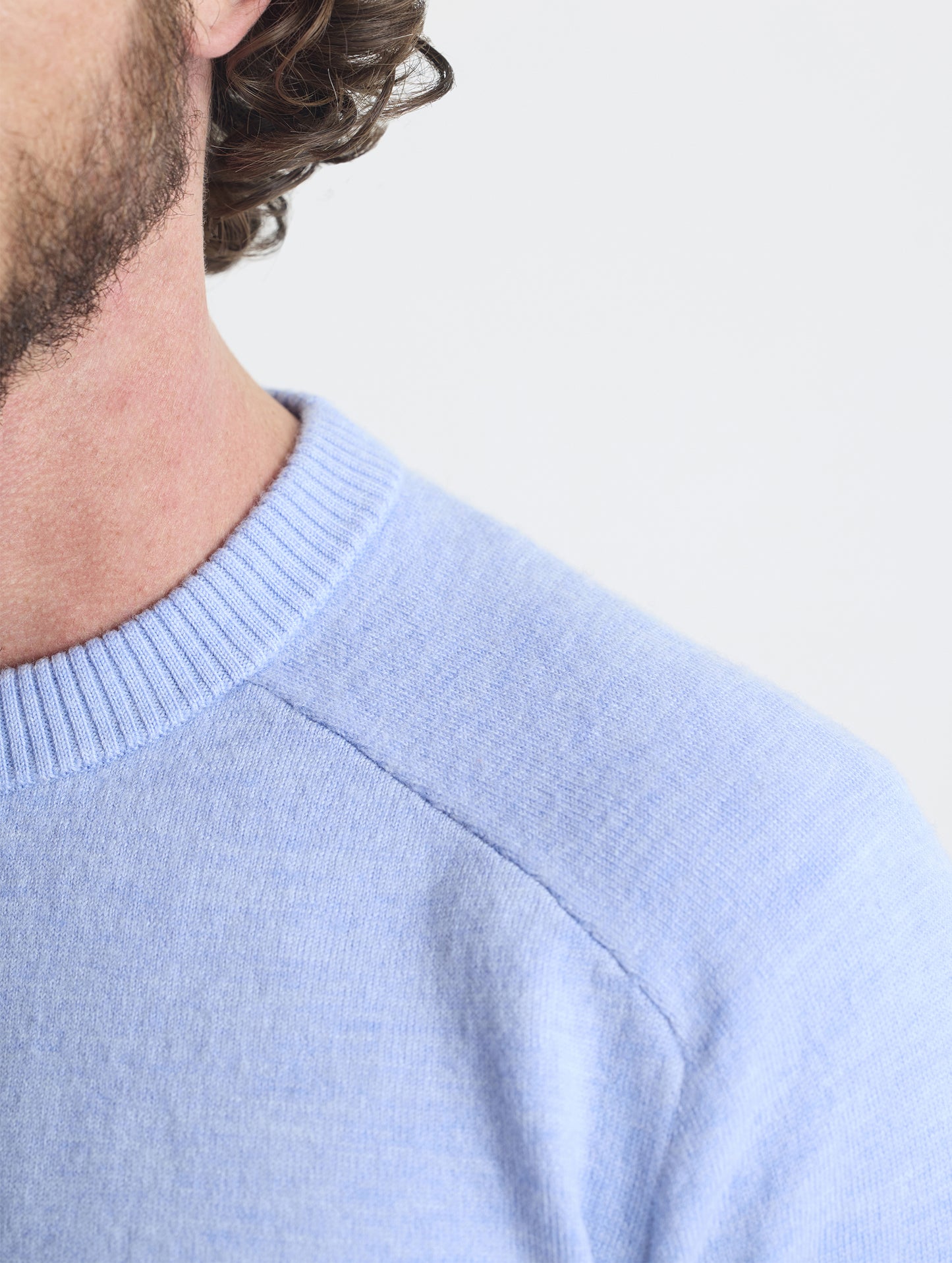 Closeup detail view of wearer's left shoulder stitch of Corbin Sweater in Light Blue Heather from AETHER Apparel.