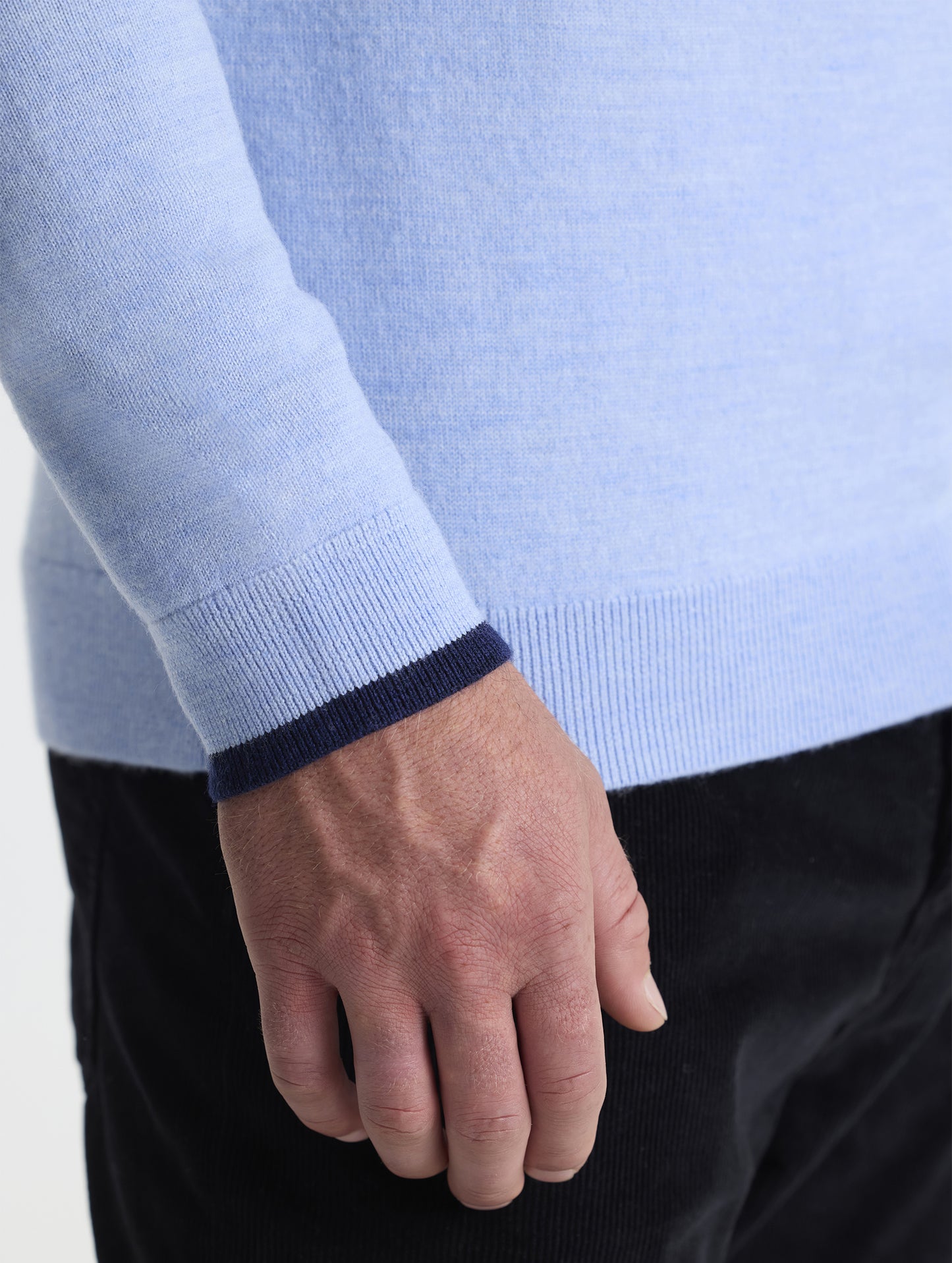 Closeup detail view of wearer's right sleeve of Corbin Sweater in Light Blue Heather contrast dark blue hem from AETHER Apparel.
