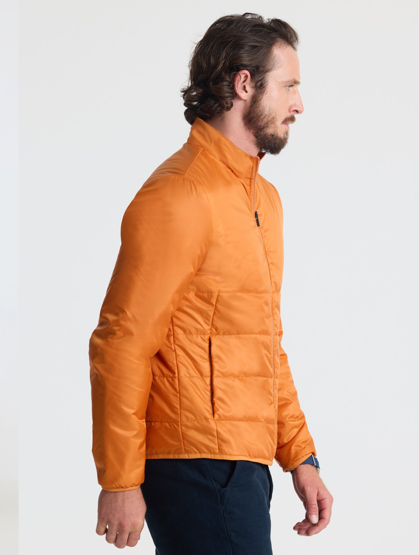 Right profile view of man wearing Eco Insulated Jacket in Autumn Orange from AETHER Apparel.