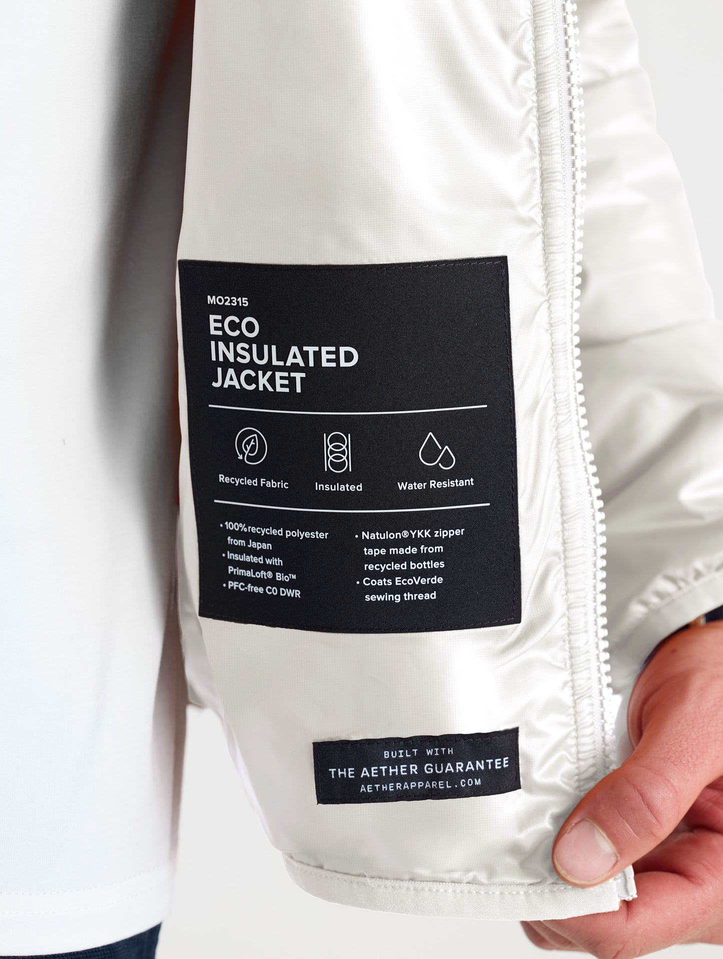 Closeup view of wearer's left interior label of Eco Insulated Jacket in Bone white from AETHER Apparel.