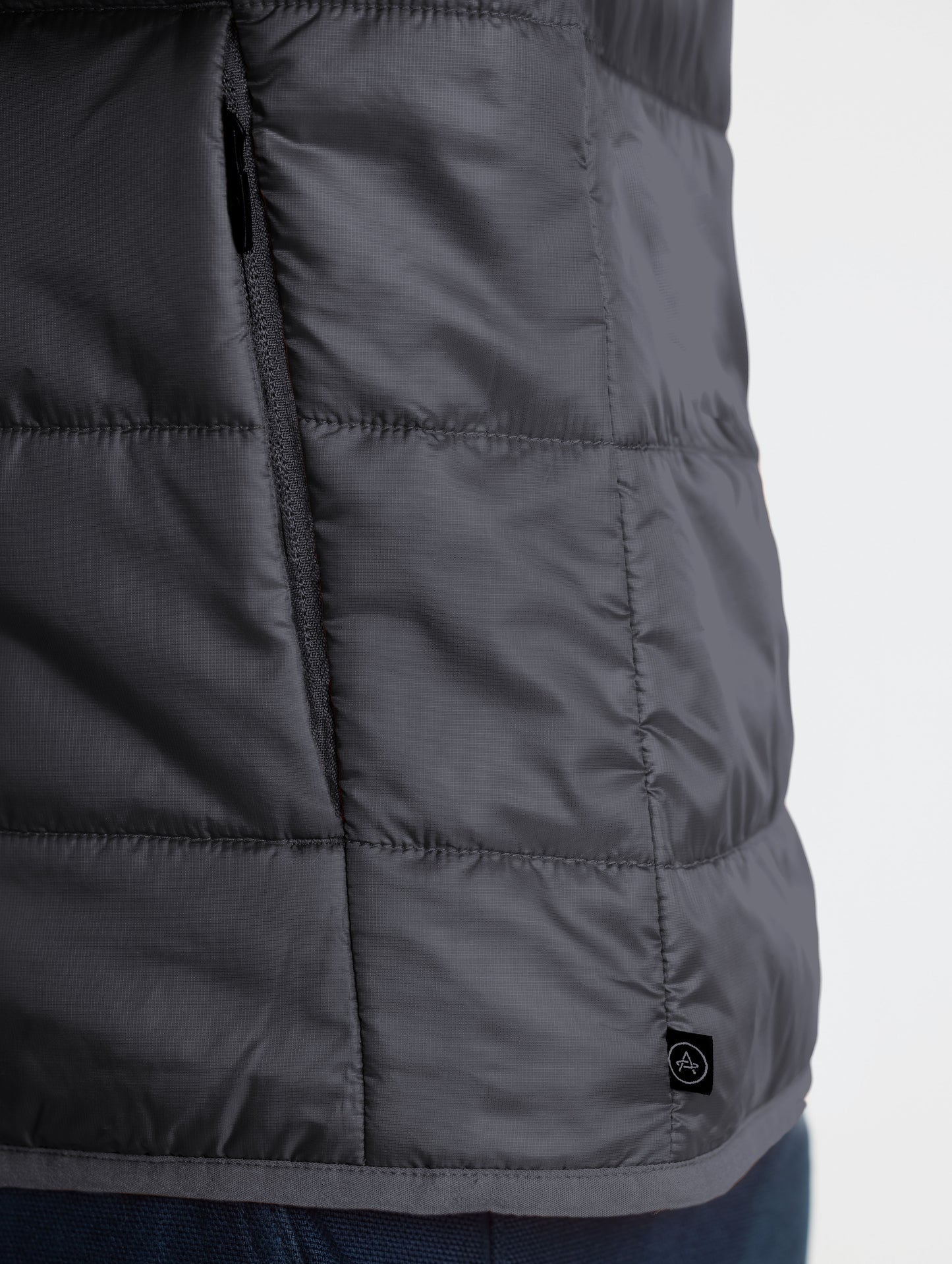 Closeup view of wearer's left hand pocket of Eco Insulated Jacket in Onyx Black from AETHER Apparel.