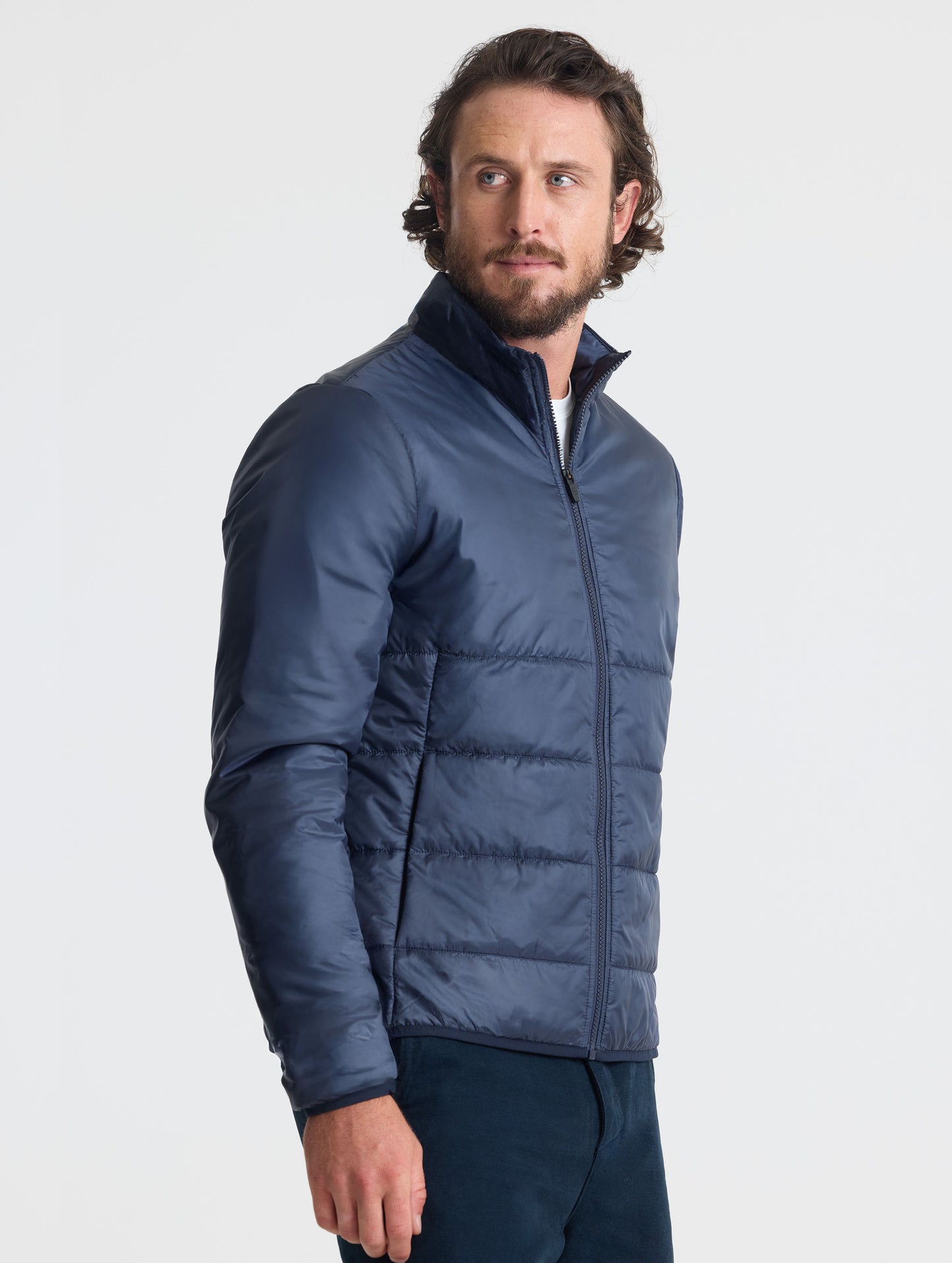 Angled view of man wearing Eco Insulated Jacket in Total Eclipse dark blue from AETHER Apparel.