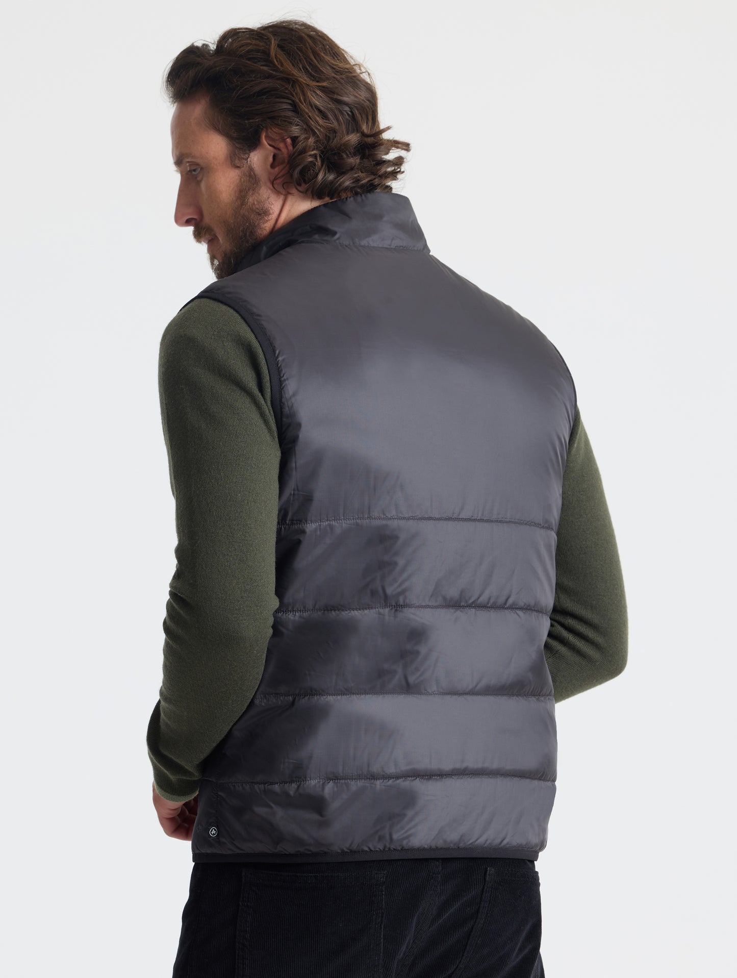 Rear view of man wearing Eco Insulated Vest in Onyx Black from AETHER Apparel.