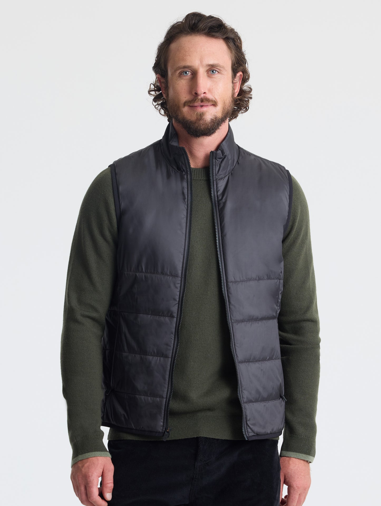 Upper body view man wearing unzipped Eco Insulated Vest in Onyx Black from AETHER Apparel.