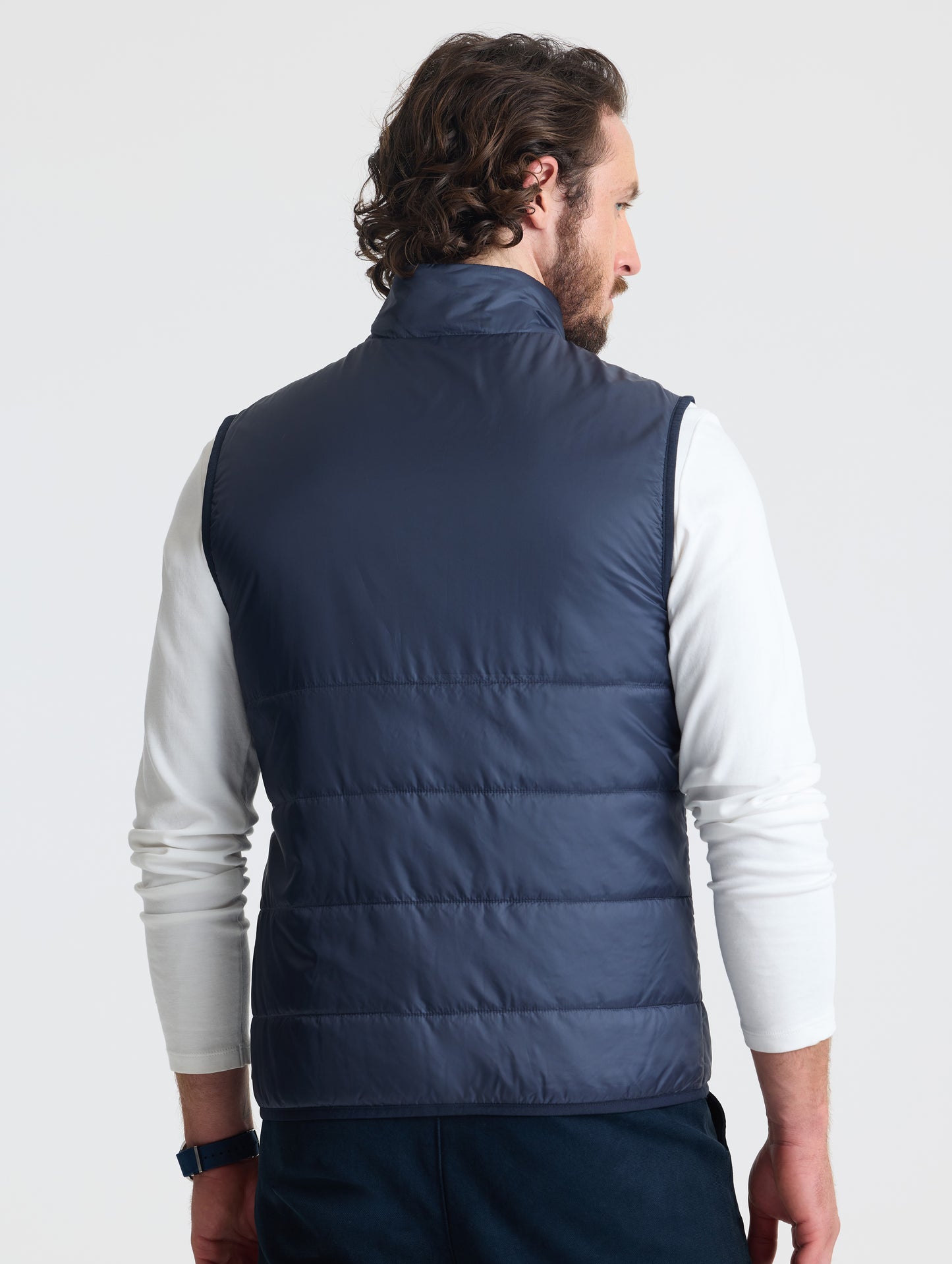 Rear view of man wearing Eco Insulated Vest in Total Eclipse dark blue from AETHER Apparel.