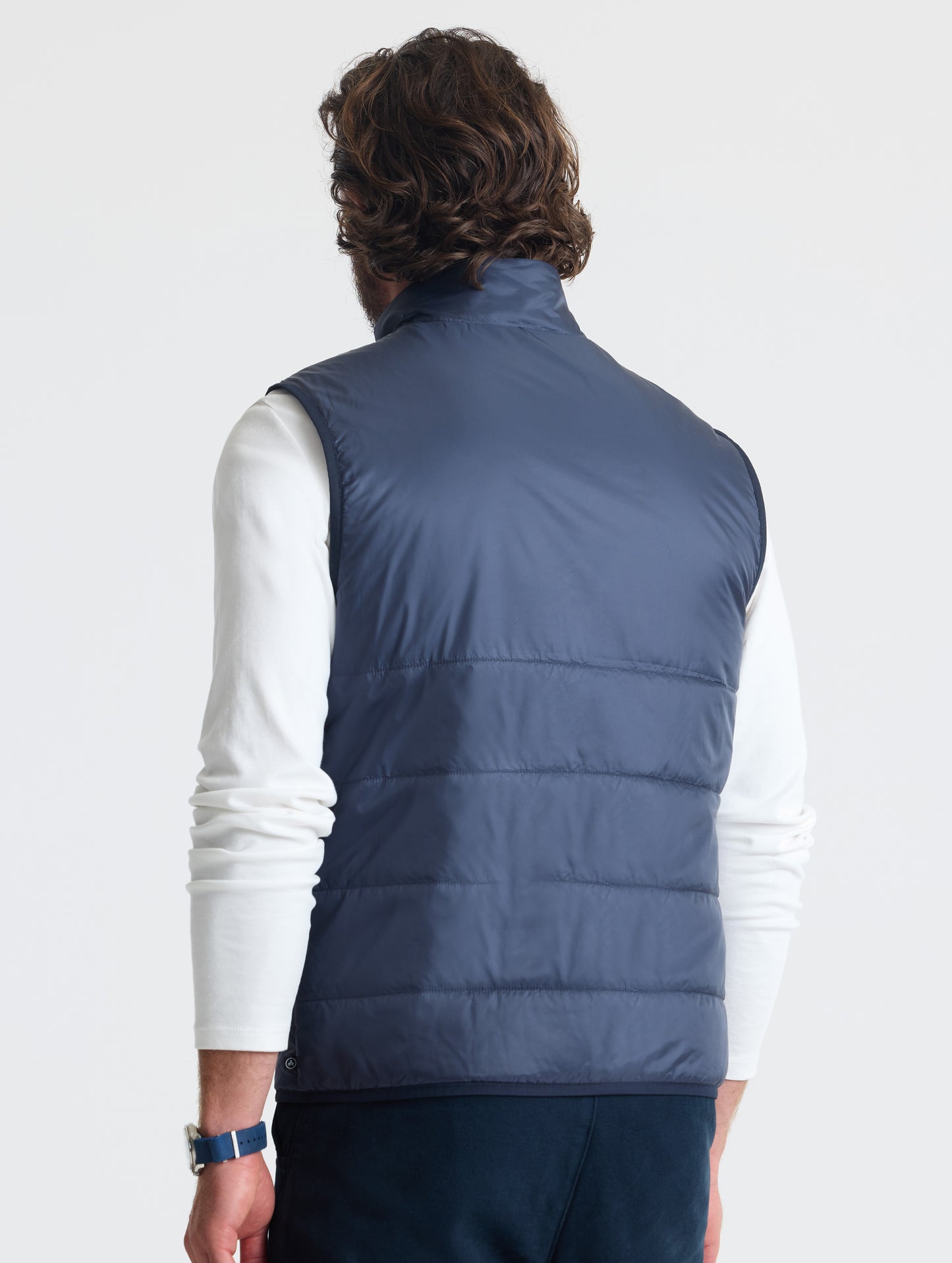 Angled rear view of man wearing Eco Insulated Vest in Total Eclipse dark blue from AETHER Apparel.