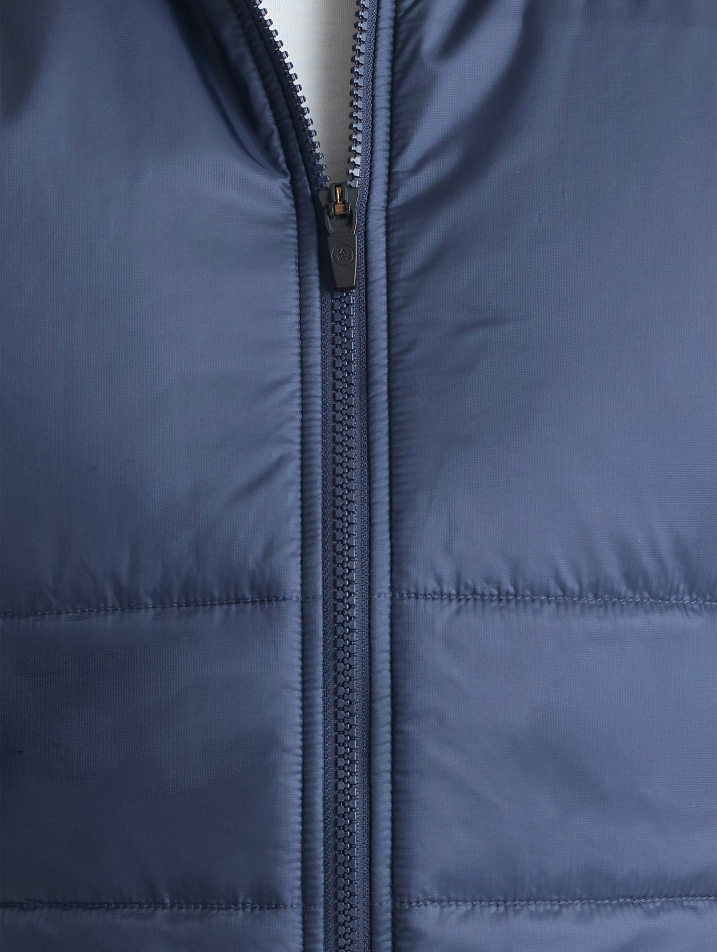 Closeup view of front center zipper of Eco Insulated Vest in Total Eclipse dark blue from AETHER Apparel.