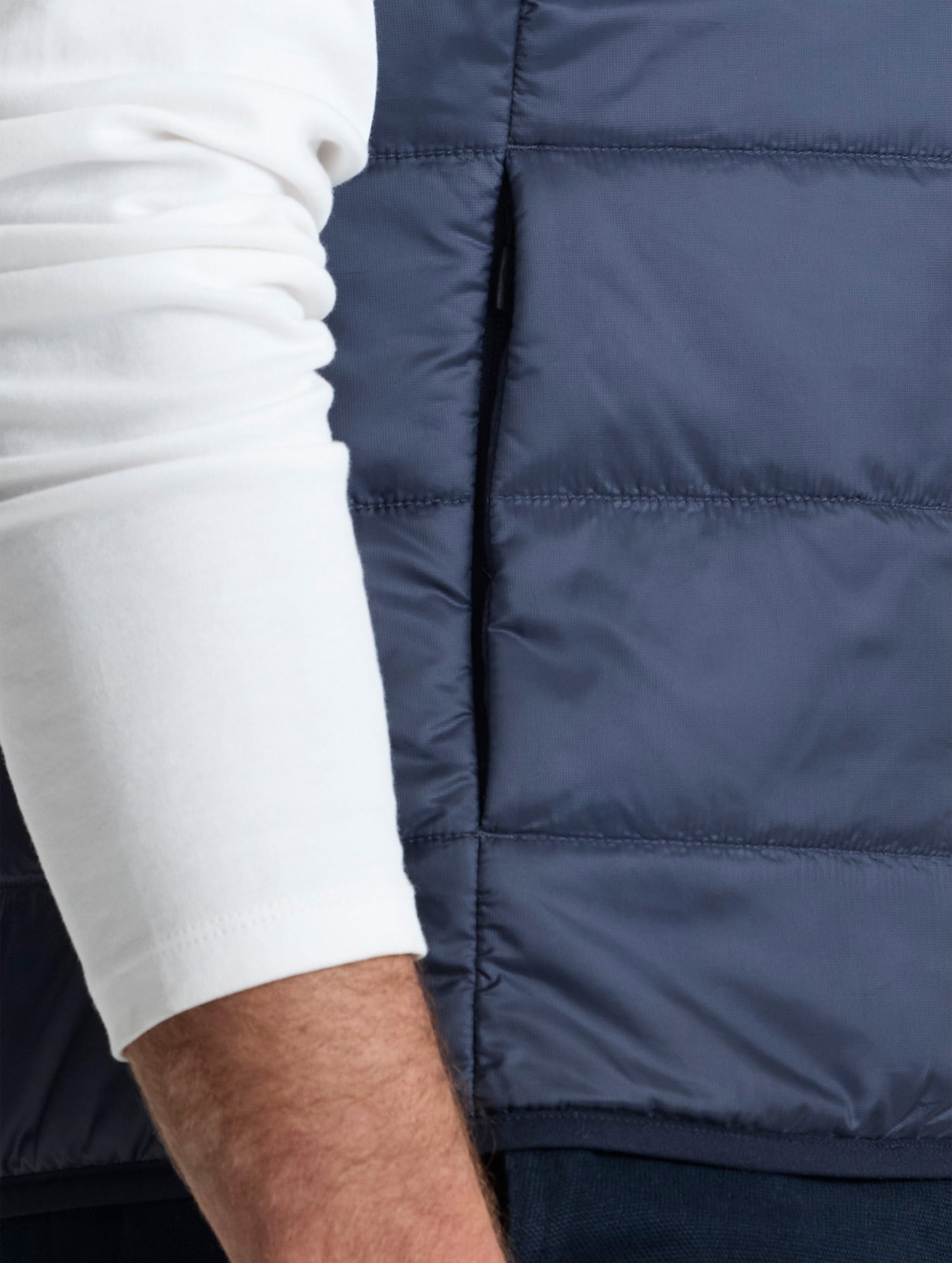 Closeup view of wearer's right hand pocket of Eco Insulated Vest in Total Eclipse dark blue from AETHER Apparel.