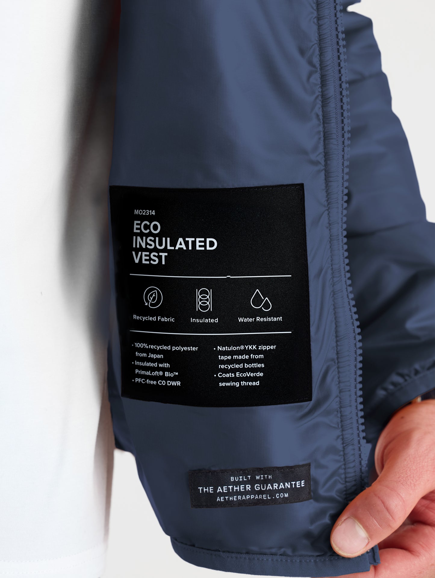 Closeup view of wearer's left interior label of Eco Insulated Vest in Total Eclipse dark blue from AETHER Apparel.
