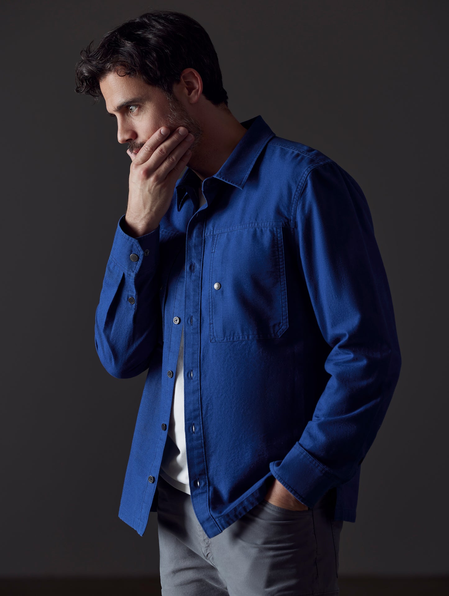 Front 3/4 body view of man with hand in pant pocket wearing Emerson Button Down in Dark Blue from AETHER Apparel.