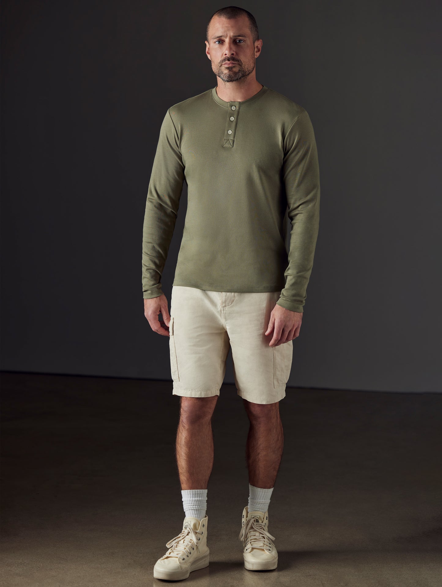 Front 3/4 full-body view of man wearing Emery Pima Henley in Fern Green from AETHER Apparel.