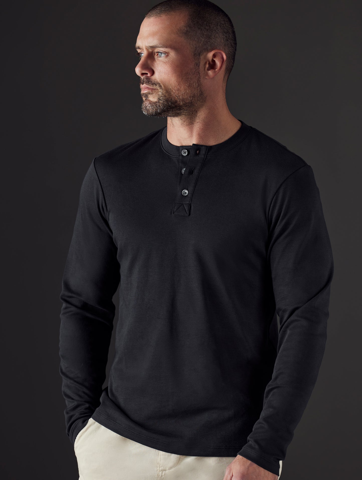 Front body view of man wearing Emery Pima Henley in Onyx Black from AETHER Apparel.