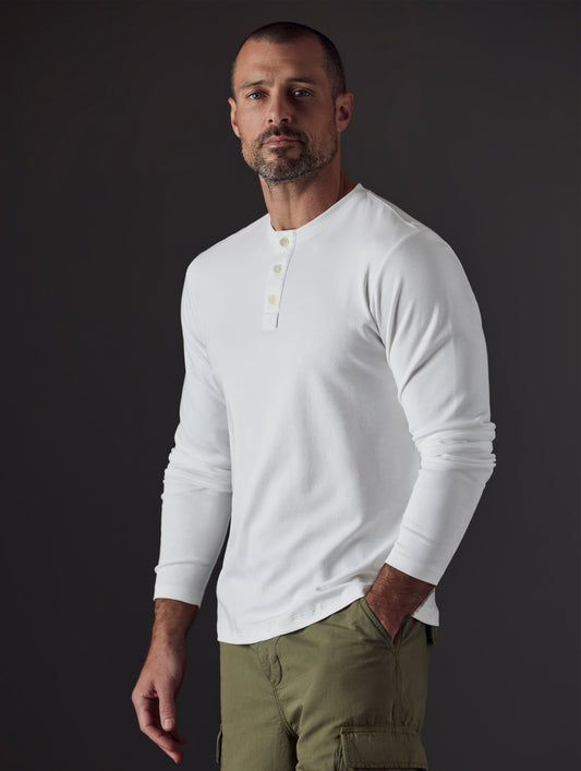 Front 3/4 body view of man with hand in pant pocket wearing Emery Pima Henley in White from AETHER Apparel.