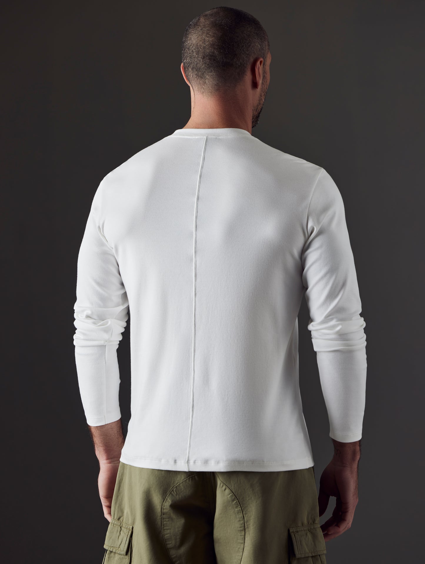 Rear 3/4 body view of man wearing Emery Pima Henley in White from AETHER Apparel.