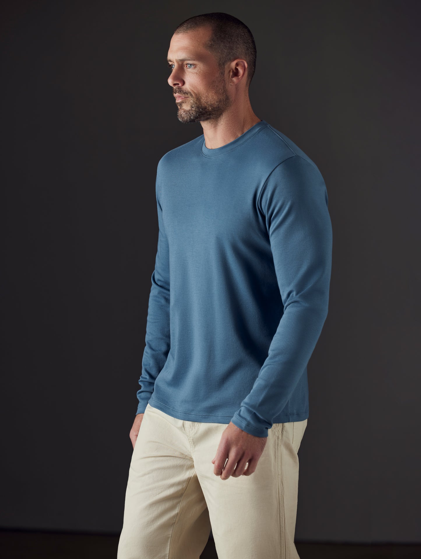 Front 3/4 body view of man wearing Emery Pima Long-Sleeve Tee in Coastal Blue from AETHER Apparel.