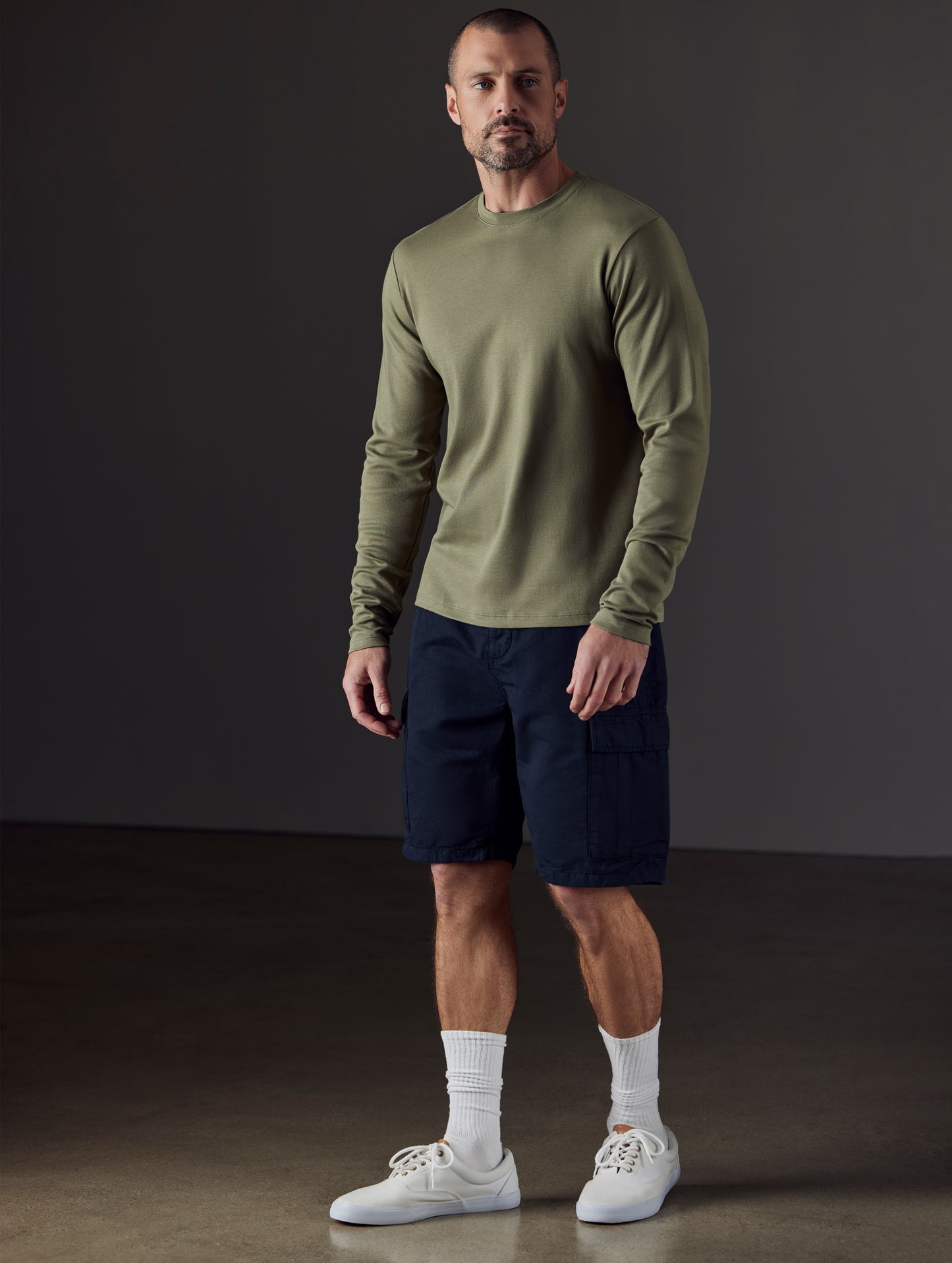 Front 3/4 full-body view of man wearing Emery Pima Long-Sleeve Tee in Fern Green from AETHER Apparel.