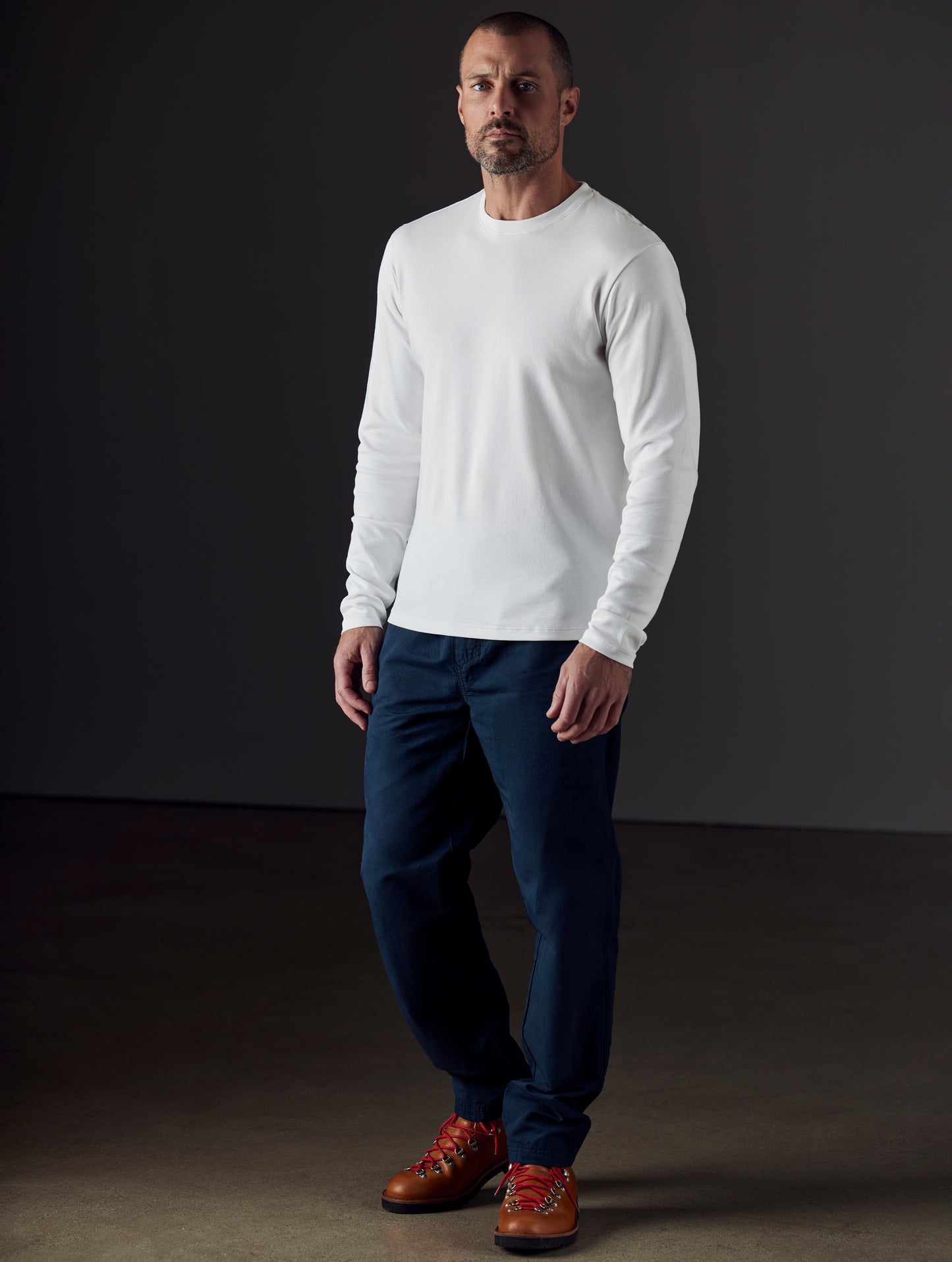 Front 3/4 full-body view of man wearing Emery Pima Long-Sleeve Tee in White from AETHER Apparel.