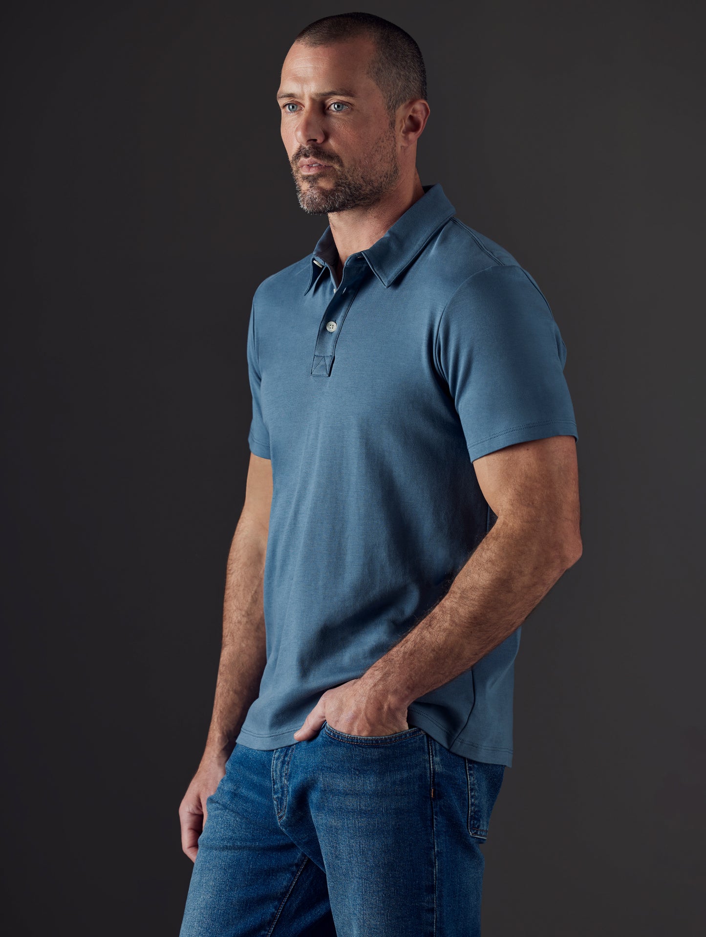 Front 3/4 body view of man wearing Emery Pima Polo in Coastal Blue from AETHER Apparel.