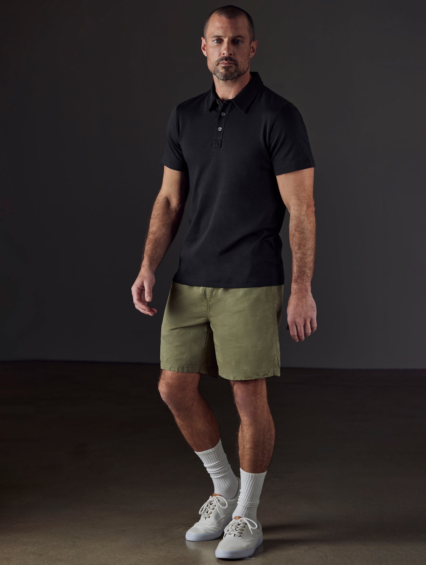 Front 3/4 full-body view of man wearing Emery Pima Polo in Onyx Black from AETHER Apparel.