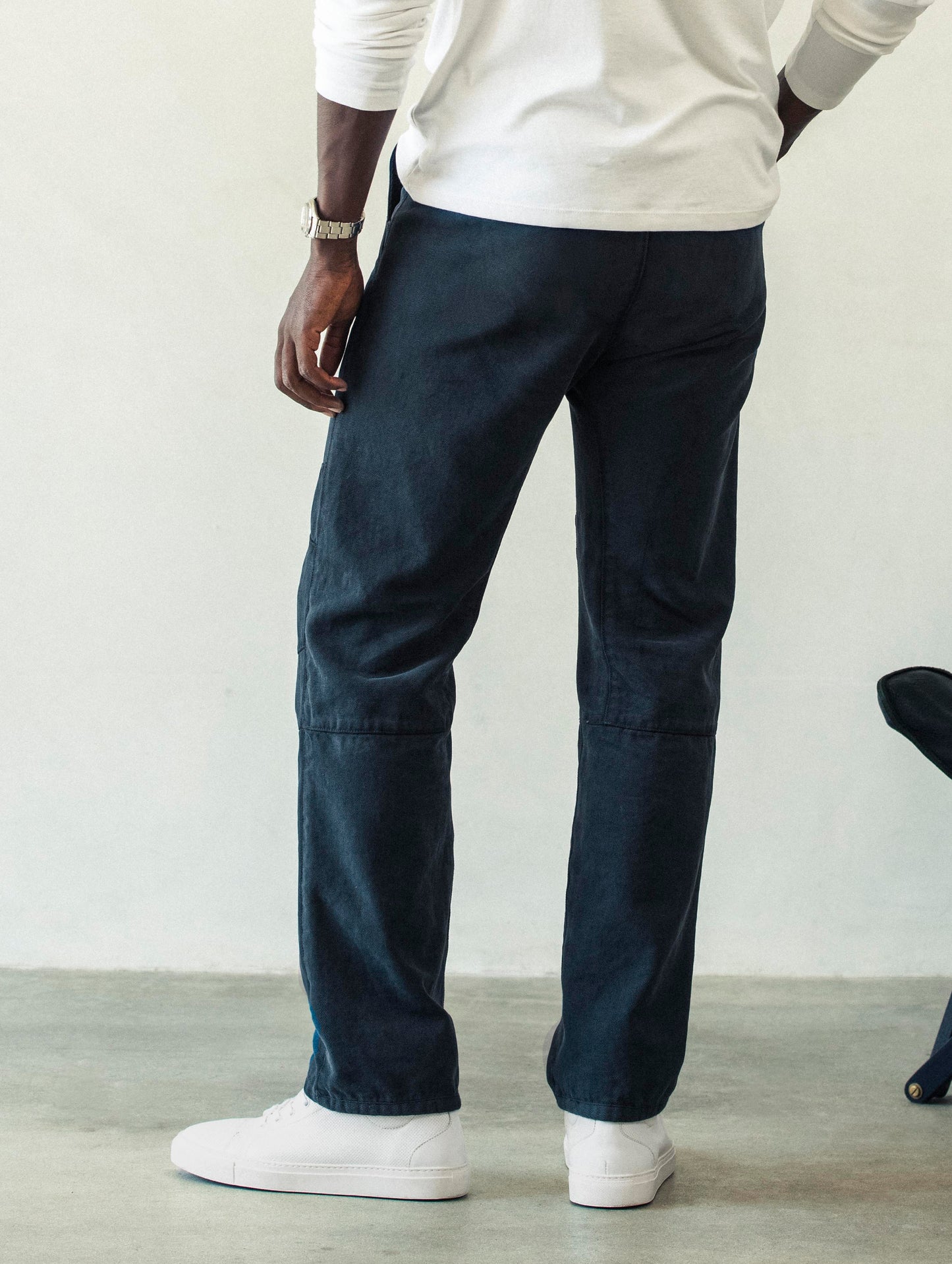Rear angled lower body view of man wearing Gabriel Articulated Chino Stretch pant in Total Eclipse dark blue from AETHER Apparel.