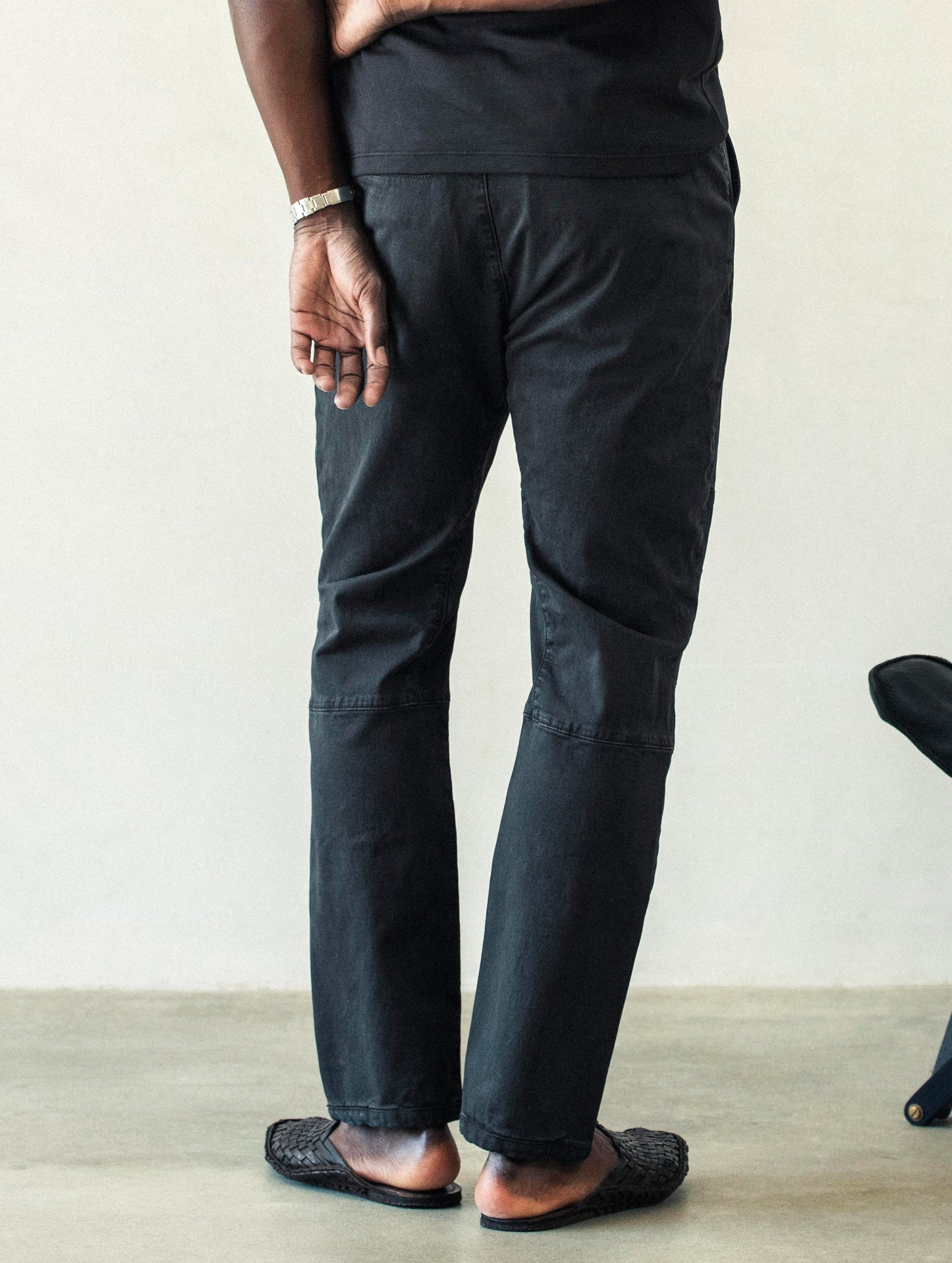 Rear lower body view of man wearing Gabriel Articulated Chino Stretch pant in Tarmac Black from AETHER Apparel.