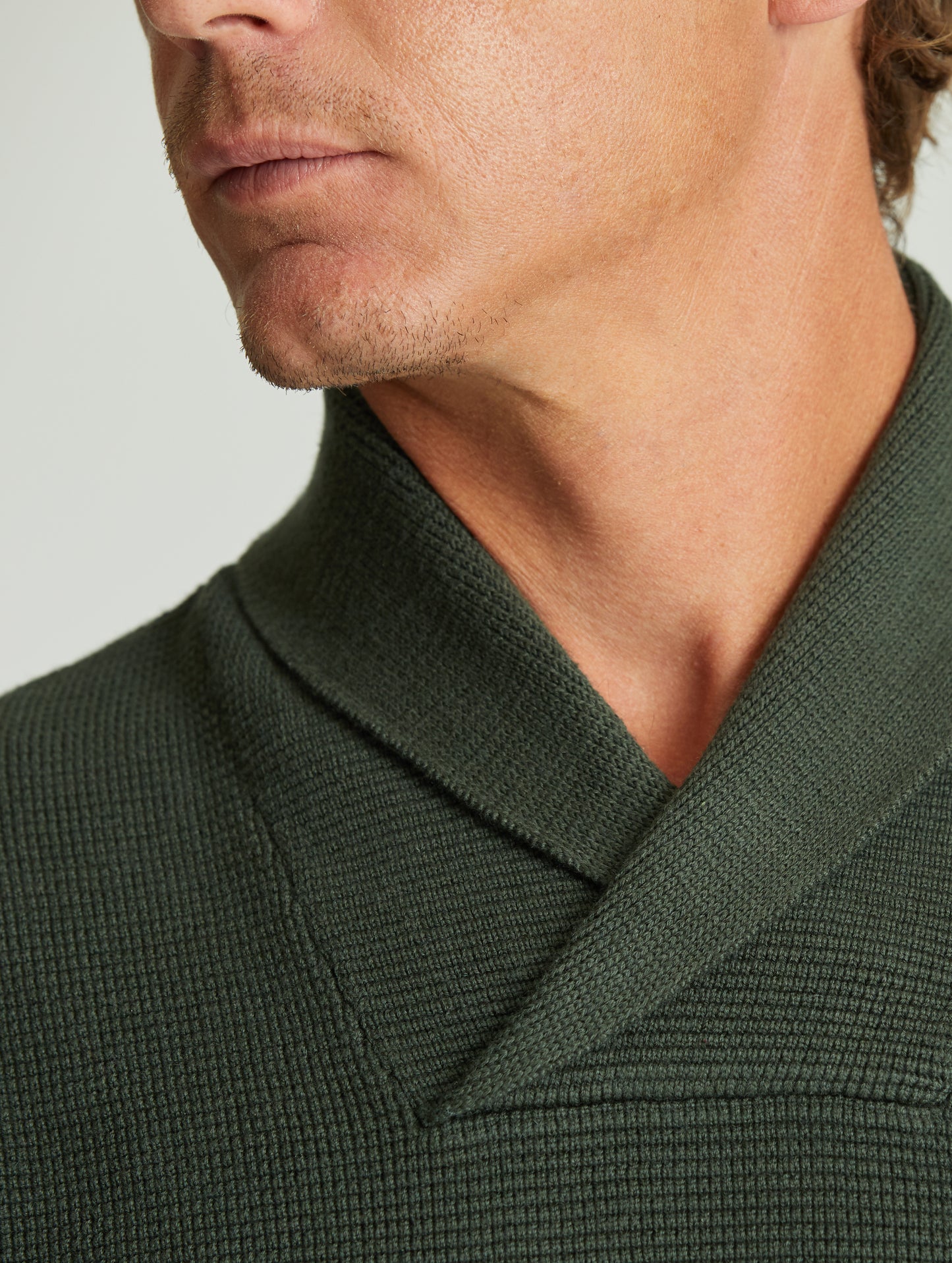 Man wearing green Gamma Sweater from AETHER Apparel, with collar in close view.