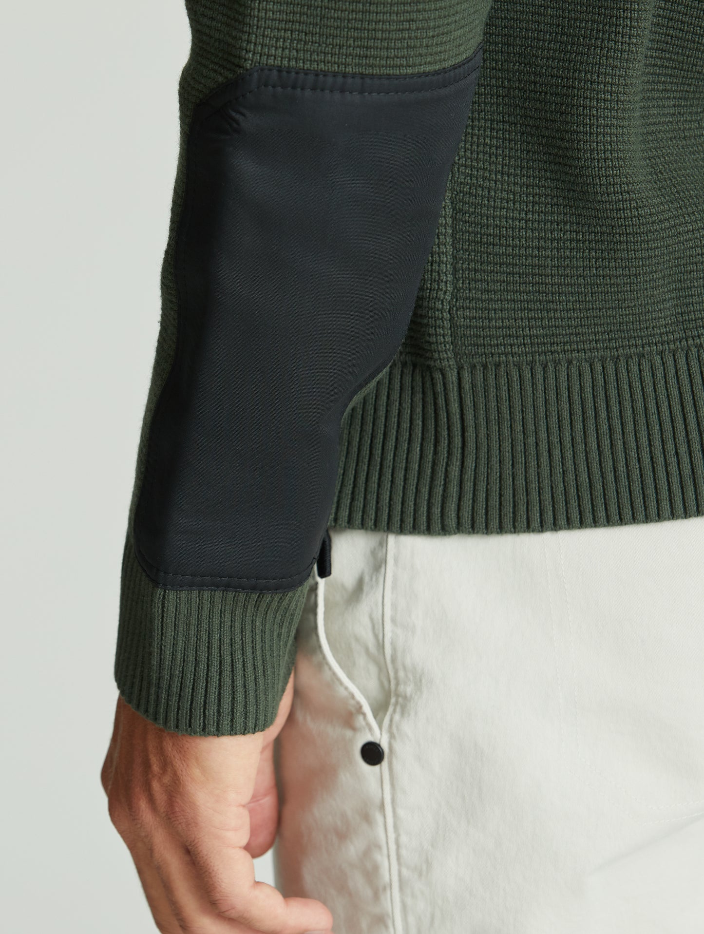 Man wearing green Gamma Sweater from AETHER Apparel, with sleeve and body hem in close view.